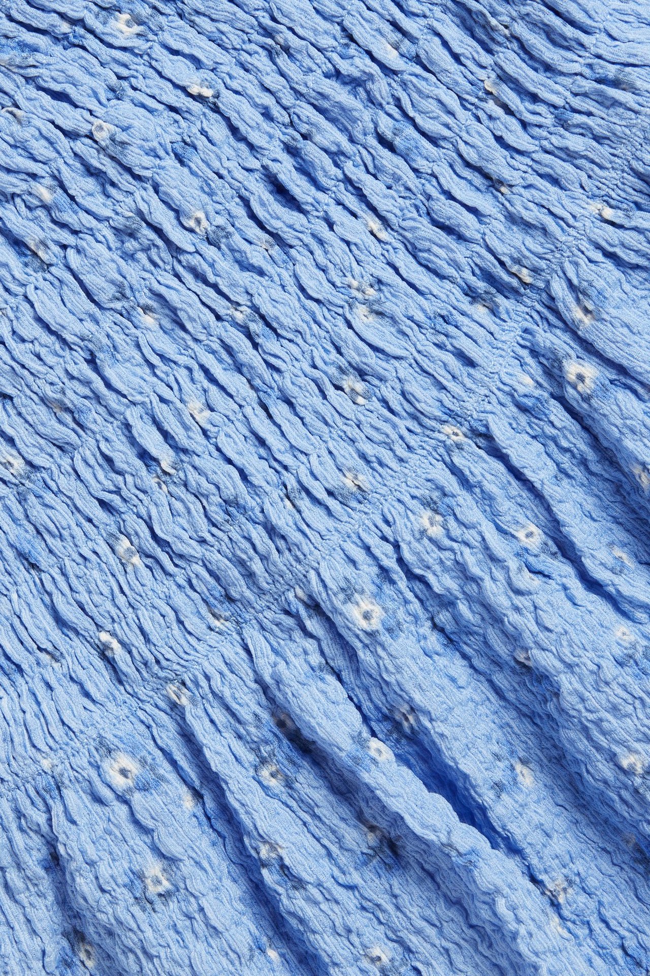 Zbliżenie na jasnoniebieski top w kwiaty z elastycznym marszczeniem, z dżerseju.