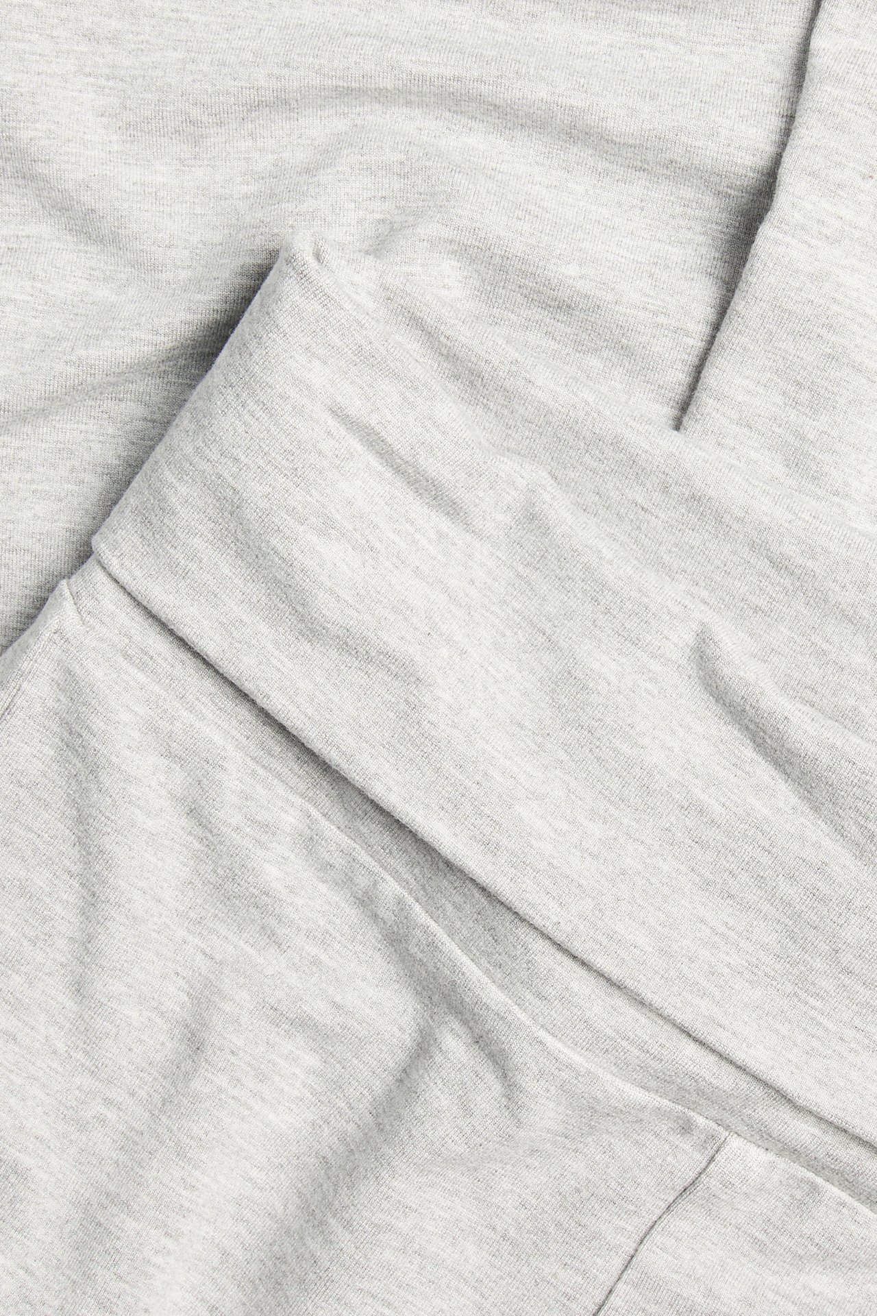 Zbliżenie na jasnoszare, melanżowe legginsy dzwony z wiskozowej mieszanki z odwijanym pasem.