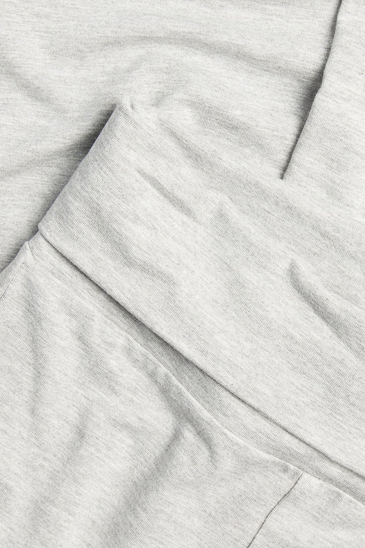 Lähikuva vaaleanharmaista meleeratuista viskoosisekoiteleggingseistä, joissa on alas käännettävä vyötärö.