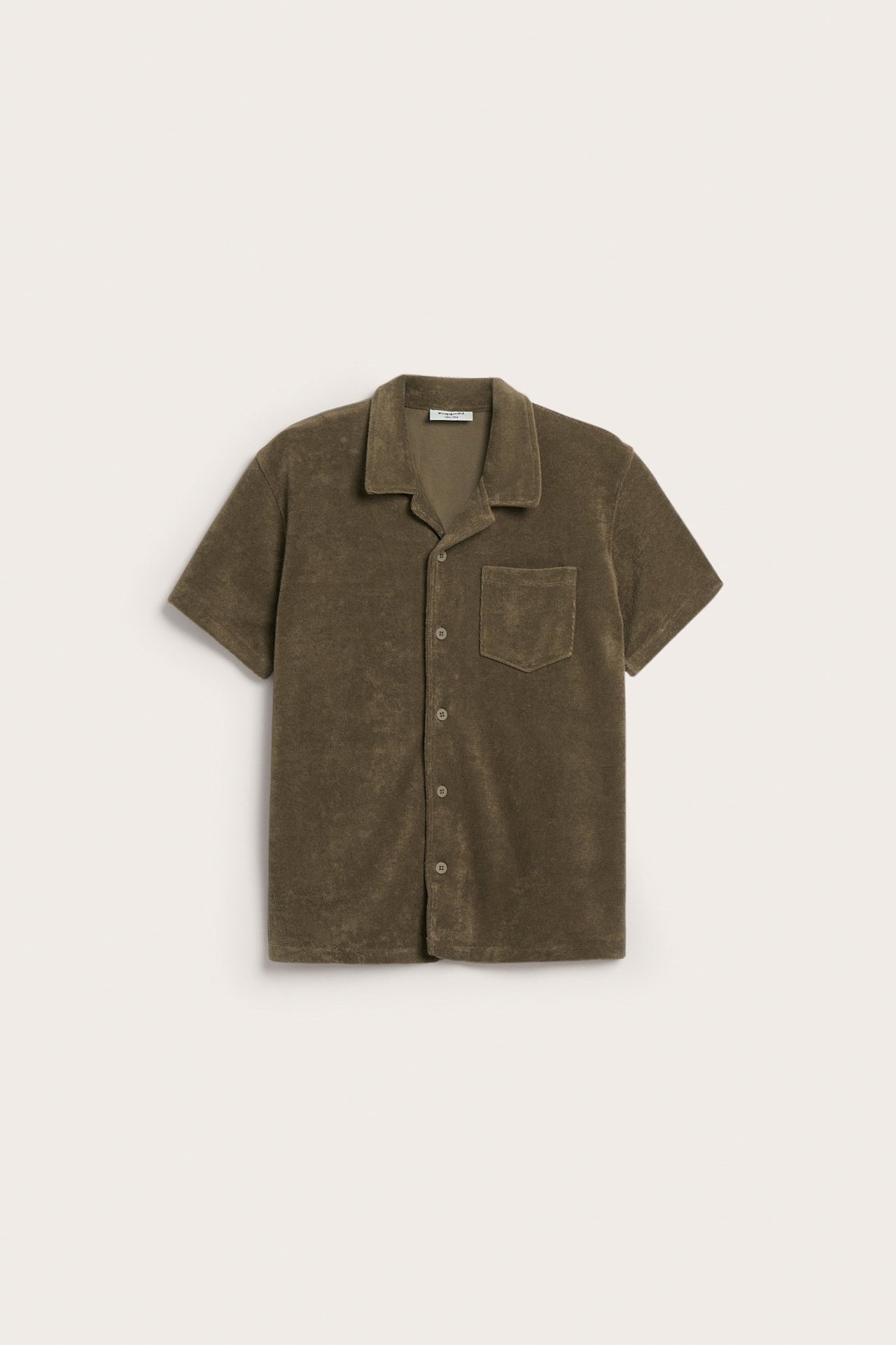 Edestä kuvattuna, ruskea lyhythihainen froteepaita resort-kauluksella, rintataskulla ja napeilla edessä.