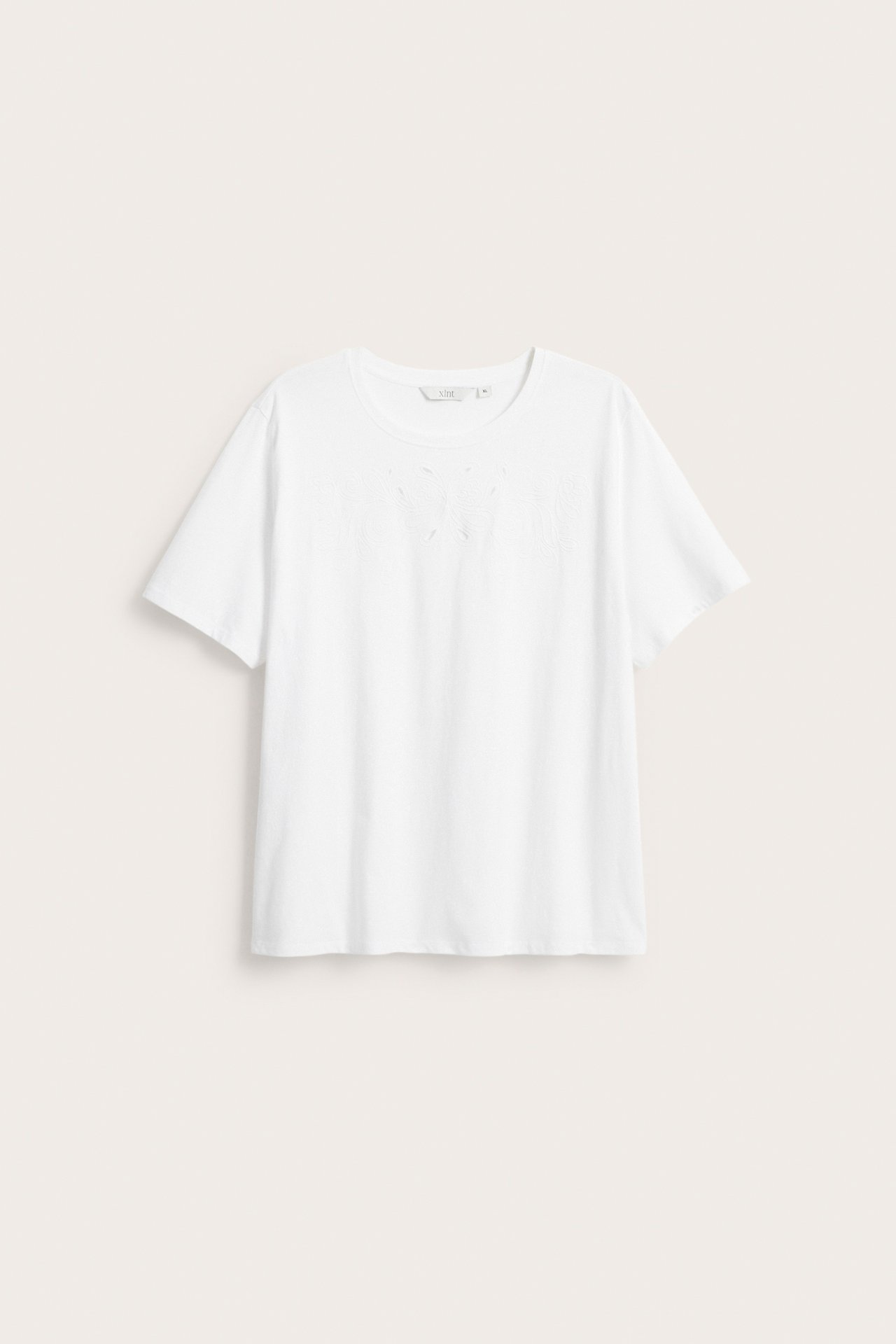 Frontvisning av en hvit bomulls-t-skjorte med korte ermer og broderie anglaise-mønster på brystet.