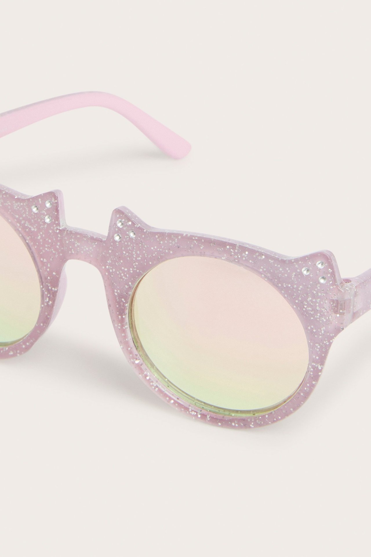 Lähikuva vaaleanpunaisista kimaltavista kissanmuotoisista aurinkolaseista peililinsseillä ja strasseilla.