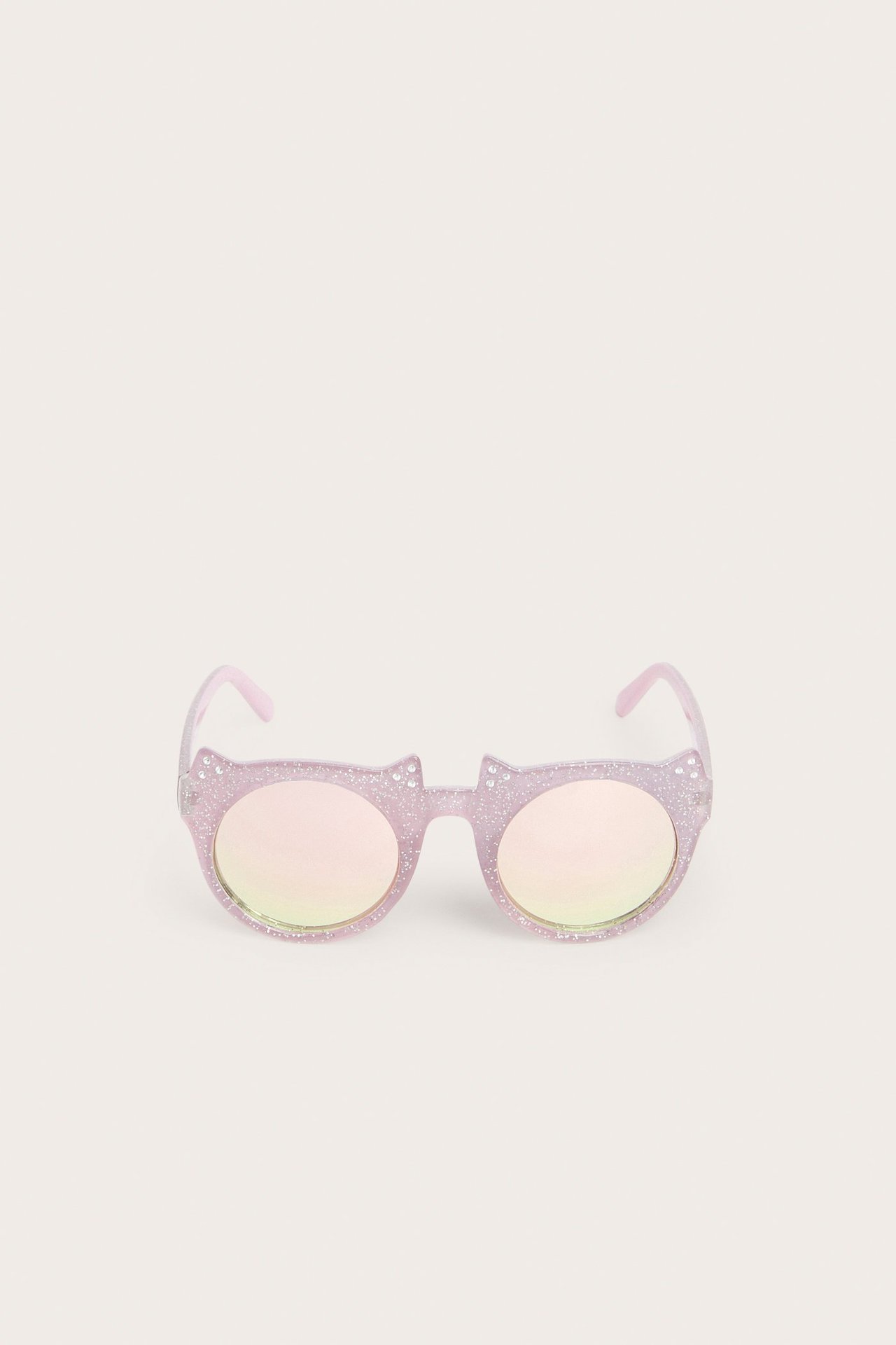 Edestä näkymä vaaleanpunaisista kimaltelevista kissanmuotoisista aurinkolaseista iirislinseillä.