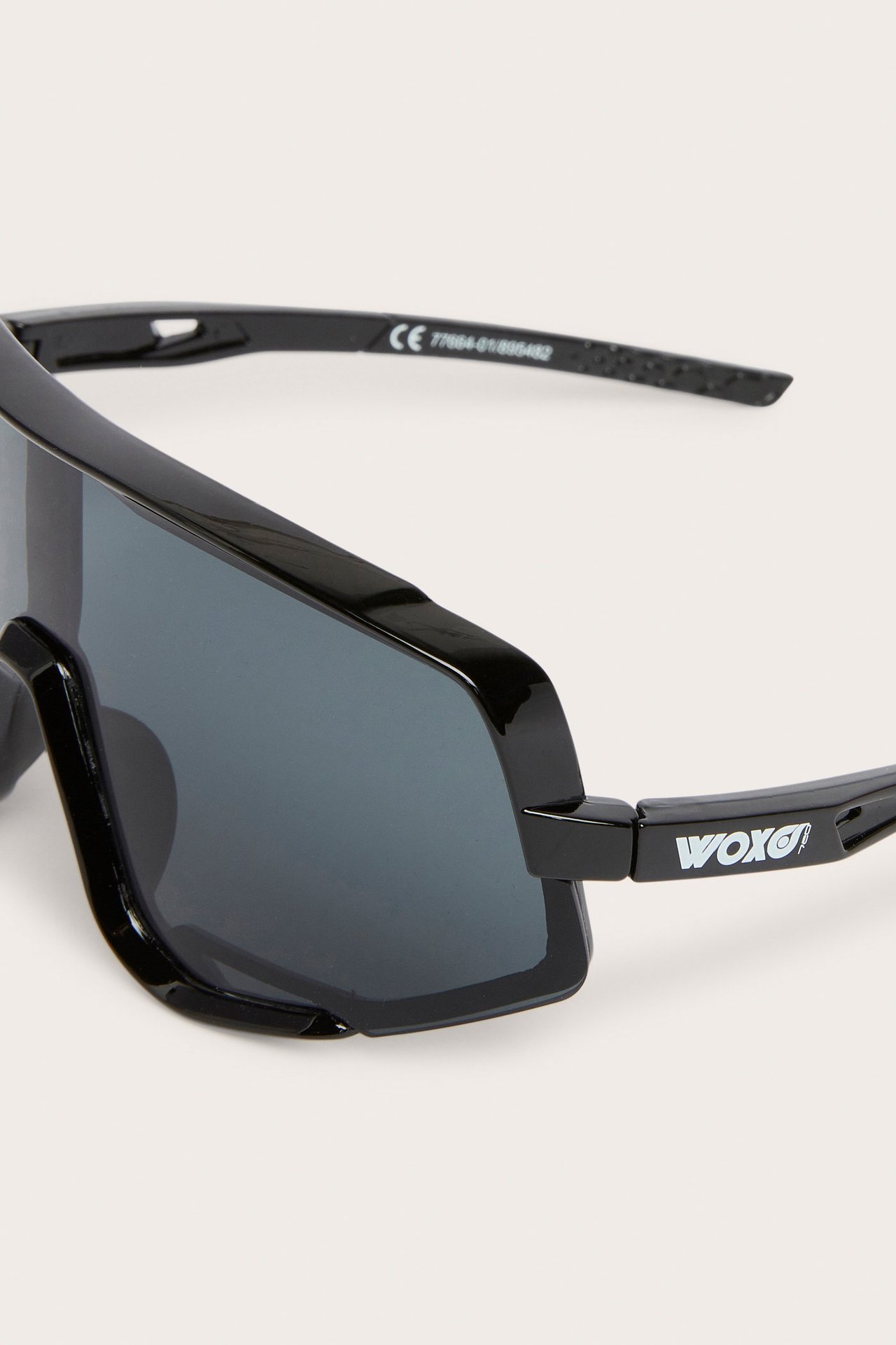 Zbliżenie na czarne, plastikowe sportowe okulary przeciwsłoneczne z dużą ciemnoszarą soczewką.