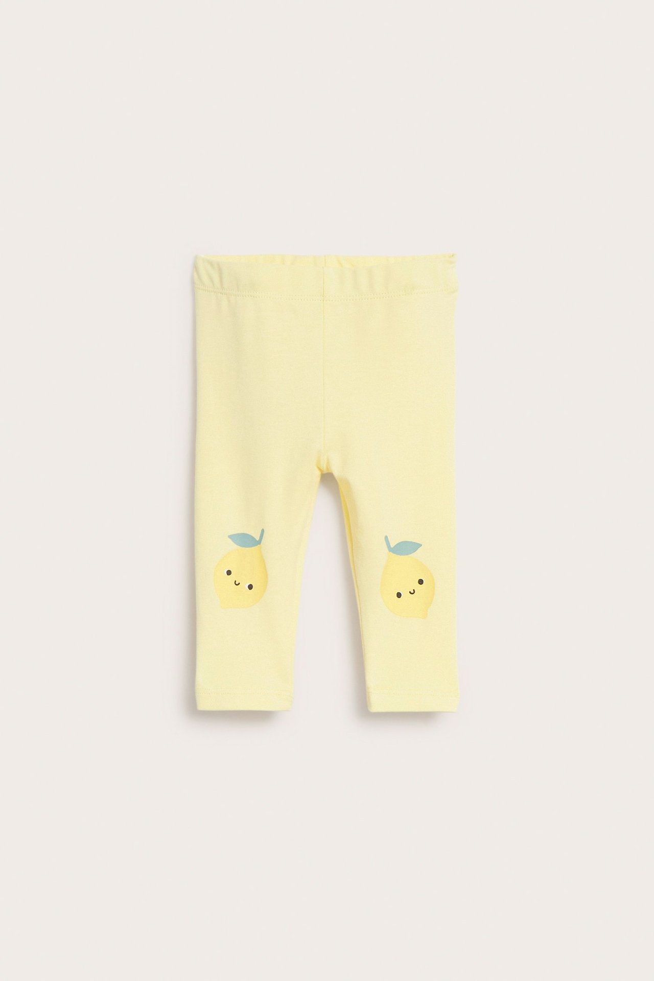 Vauvan vaaleankeltaiset puuvillasekoiteleggingsit edestä, suloisilla sitruuna-applikaatioilla polvissa.