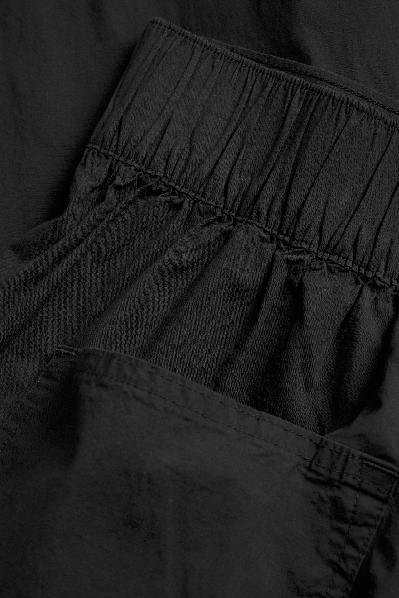 Lähikuva mustista popliinikangaisista barrel fit -housuista, joissa on kuminauha vyötäröllä.