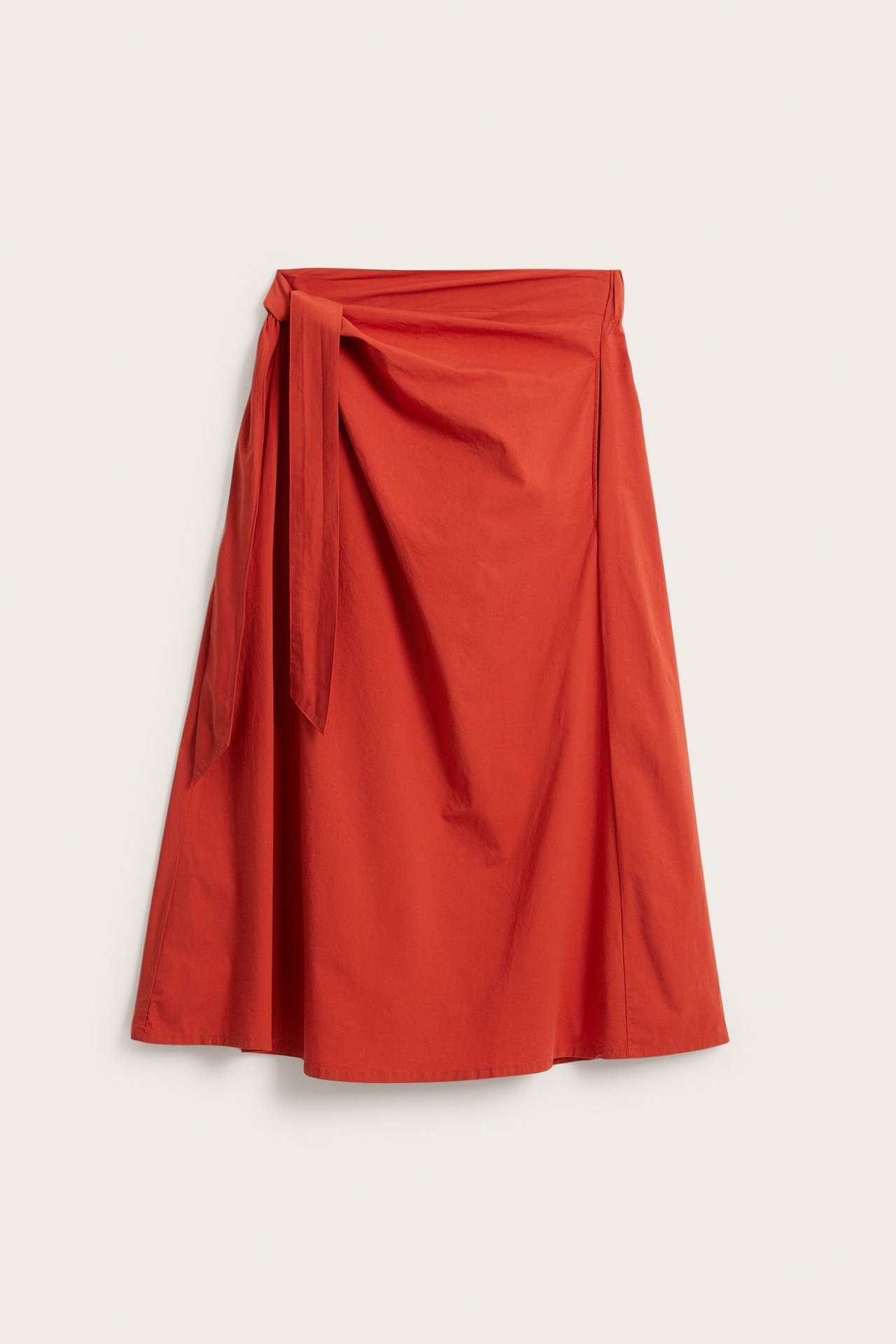 Edestäpäin näkymä punaisesta popliinisesta A-linjaisesta kietauluhameesta sivusidoksella ja joustavalla vyötäröllä.