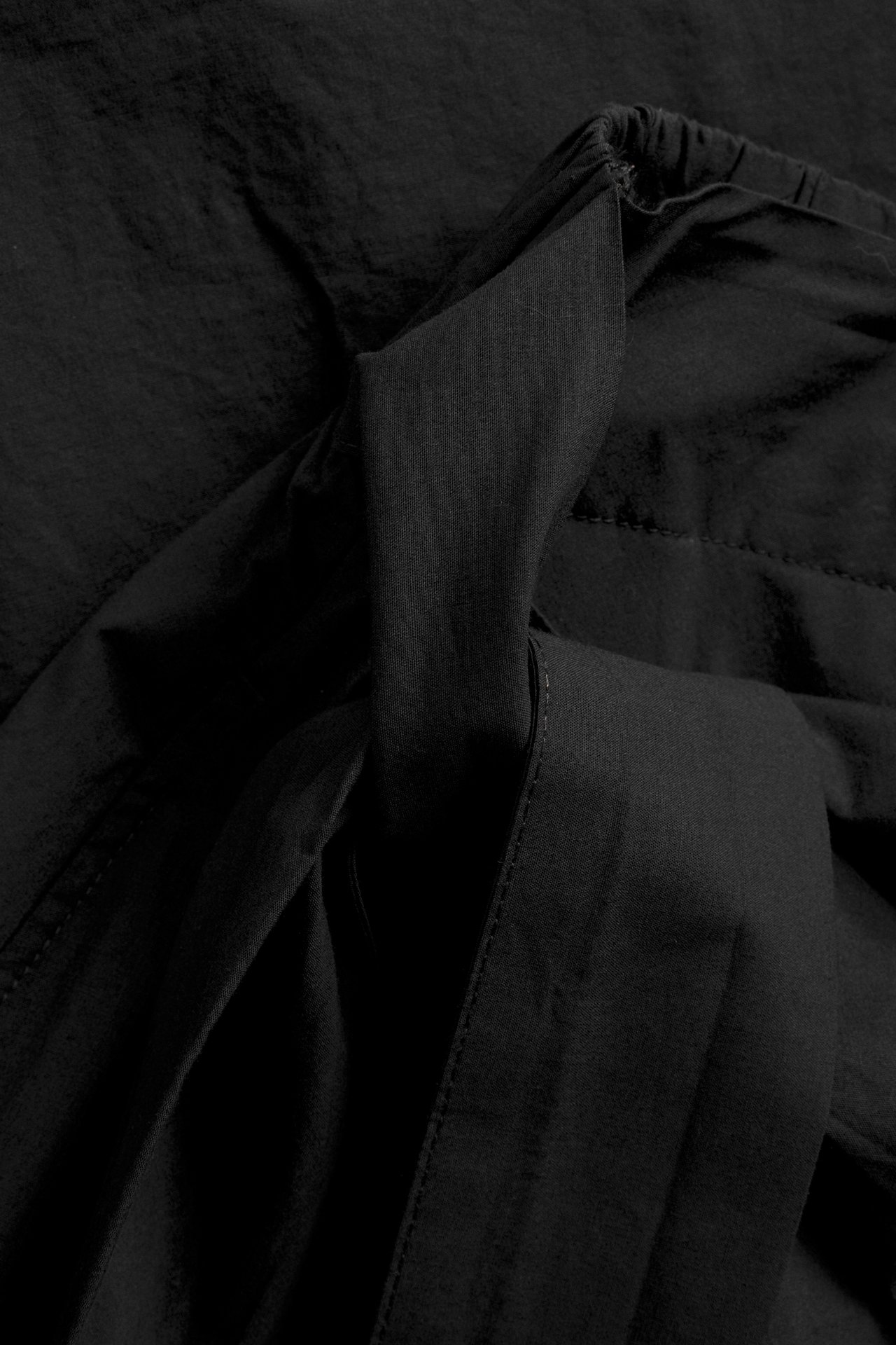 Lähikuva mustasta popliinihameesta, jossa joustava vyötärö ja solmuyksityiskohta.