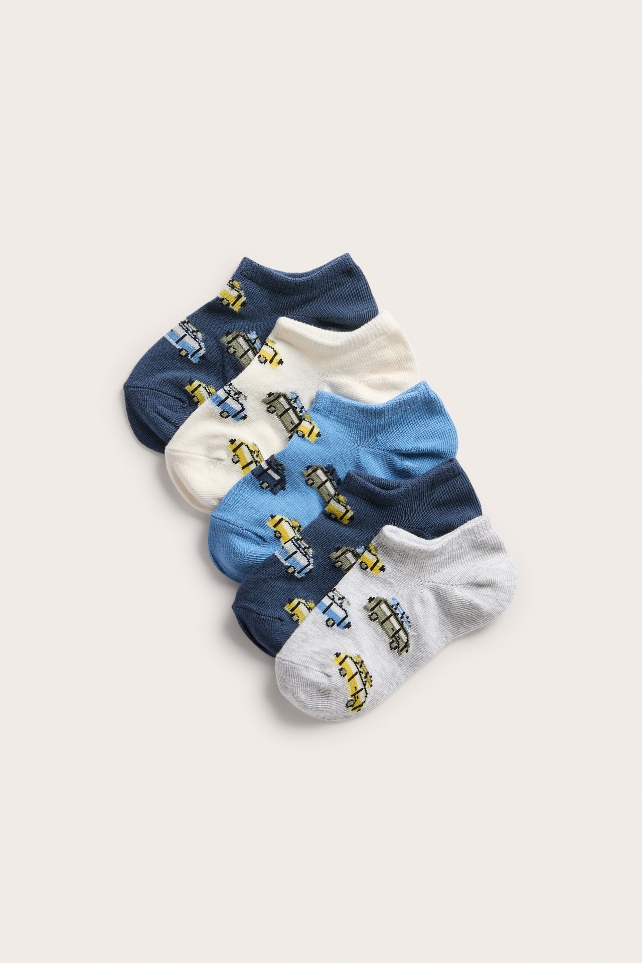 Framsida av fem par barnstrumpor i off-white, blått och grått, med färgglada fordonsmotiv.