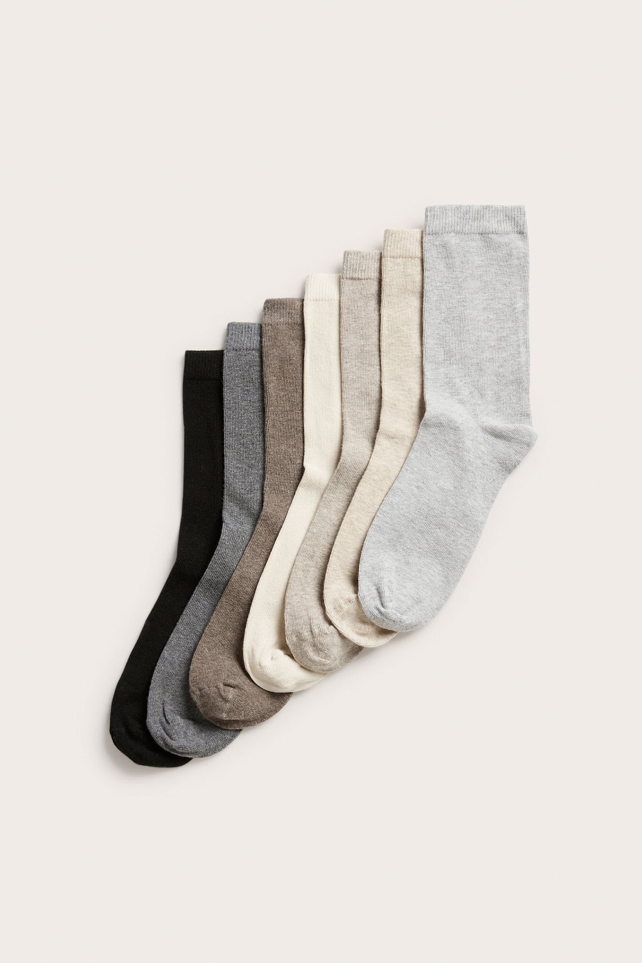 Sju par ensfargede sokker i svart, grå, brun og off-white, sett ovenfra.