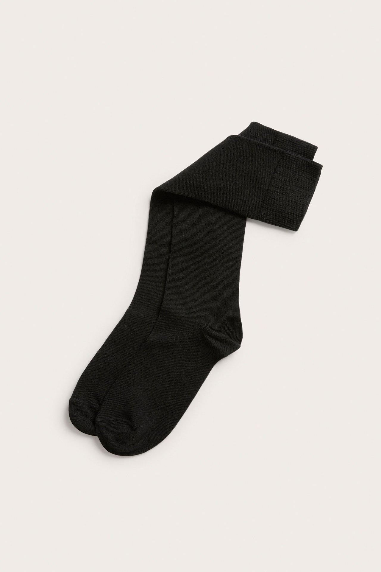 Ovenfra sett av et brettet par ensfargede sorte knestrømper i bomullsmiks med ribbekanter.