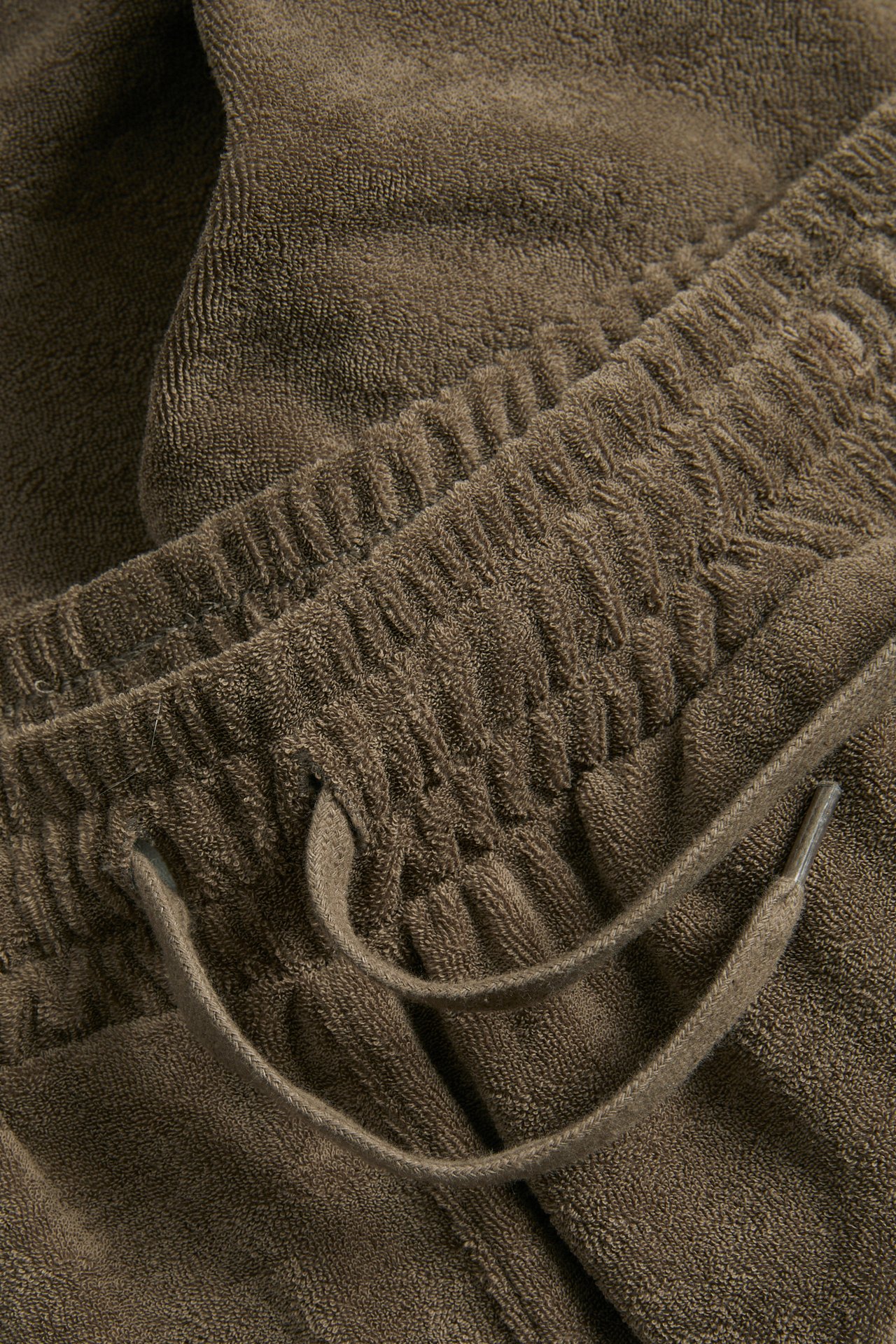 Närbild av bruna frottéshorts med elastisk midja och funktionell dragsko.