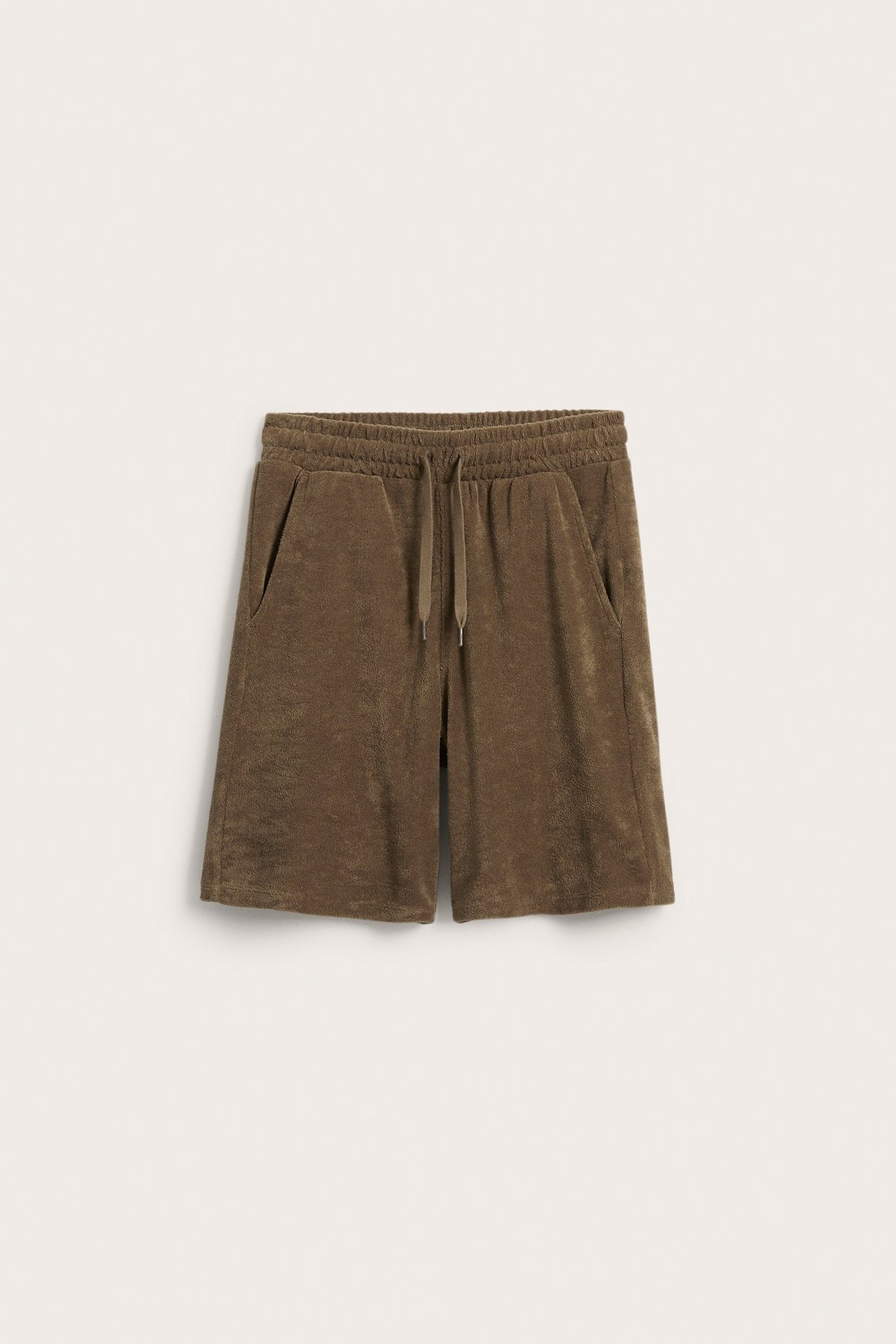 Edestäpäin, ruskeat froteeshortsit joustavalla kiristysnyörivyötäröllä ja sivutaskuilla.