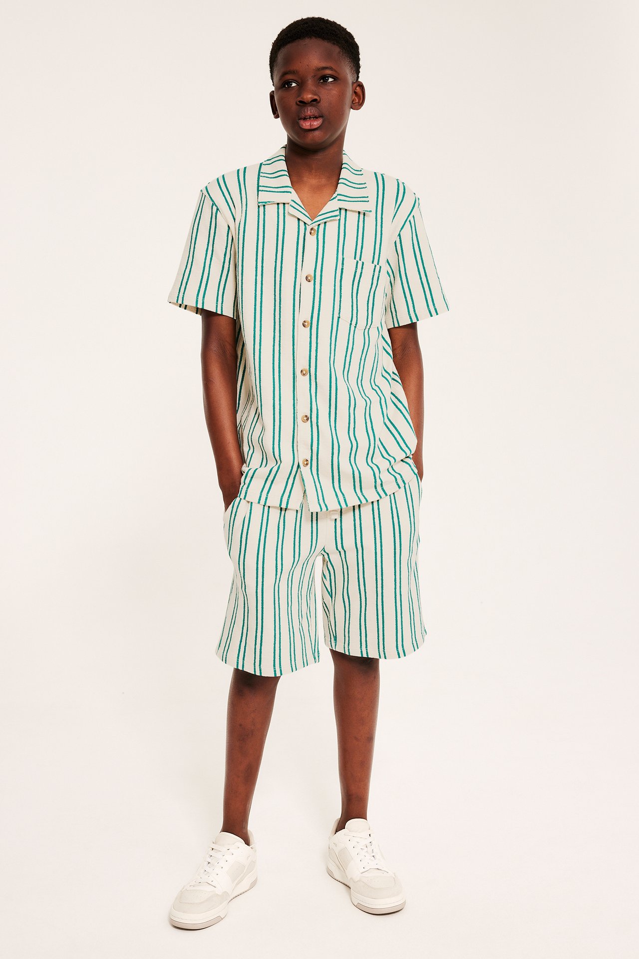 Frontvy av ett barn i randiga shorts av bomullstrikå med matchande kortärmad skjorta.