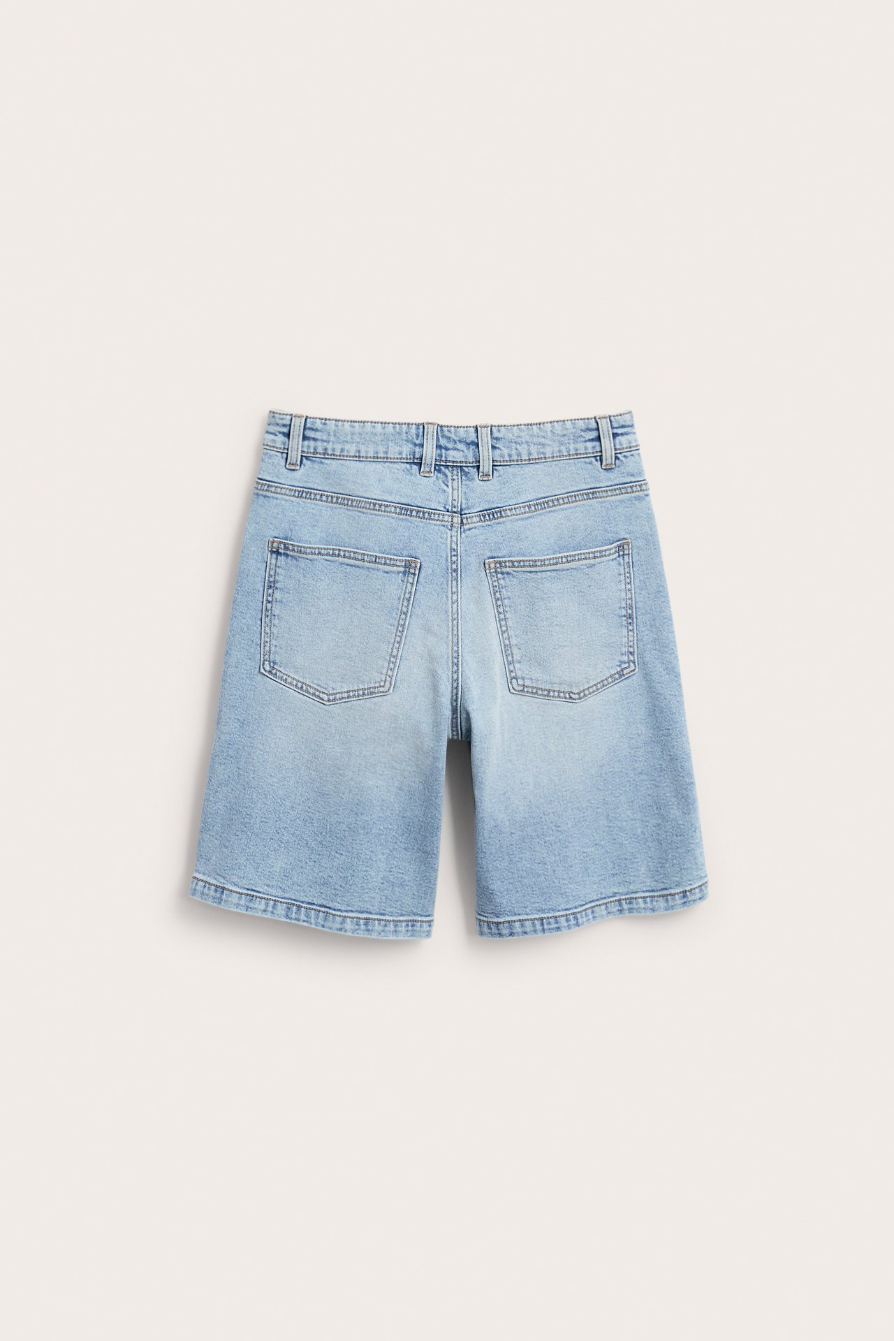 Bakvy av ljusblå enfärgade stretch denim bermudashorts med bakfickor och hällor.