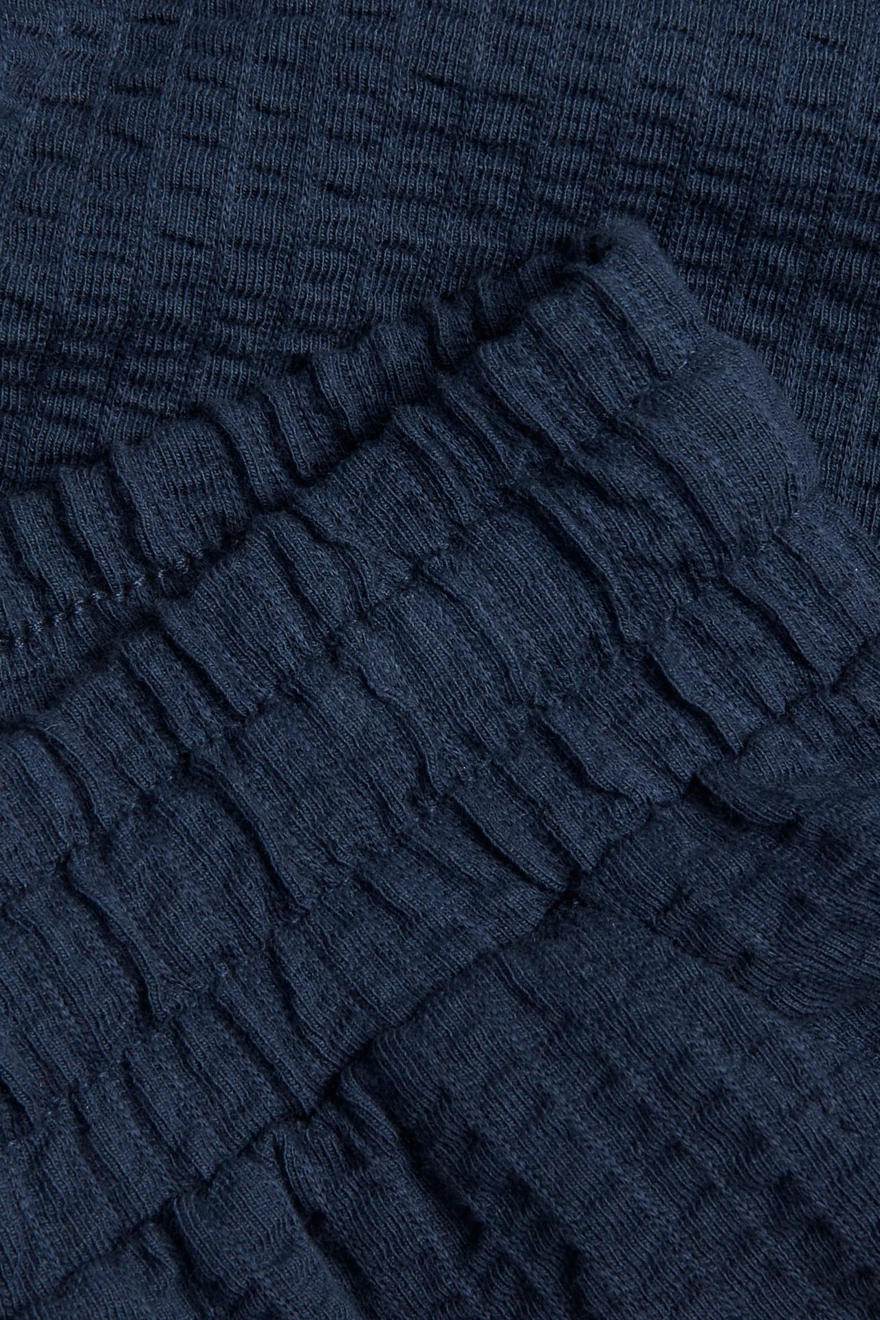 Zbliżenie na ciemnoniebieskie szorty z dżerseju seersucker z elastycznym pasem.