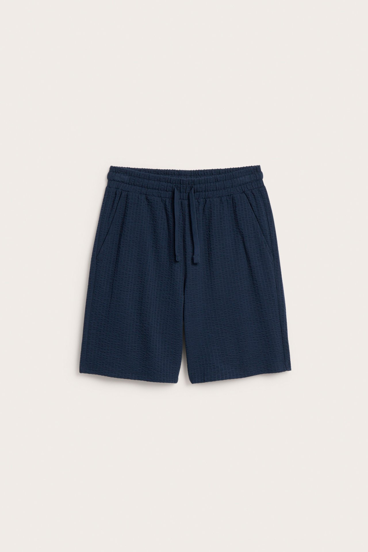Frontowy widok: granatowe szorty dziecięce z dżerseju seersucker z gumką, sznurkiem i kieszeniami.