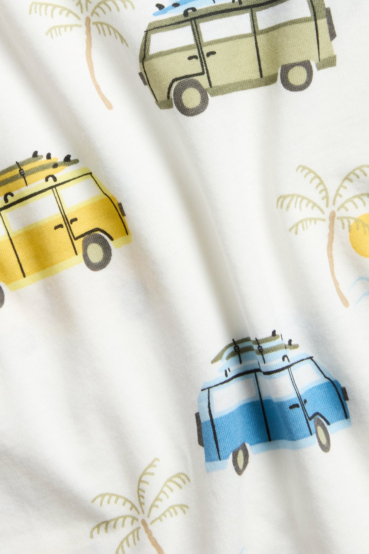 Zbliżenie: kremowy T-shirt z bawełny z nadrukiem kamperów i palm na całej powierzchni.