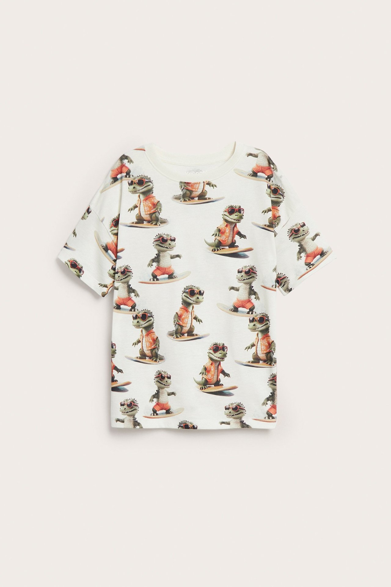 Widok z przodu na bawełnianą koszulkę dziecięcą w kolorze złamanej bieli z nadrukiem surfujących krokodyli.