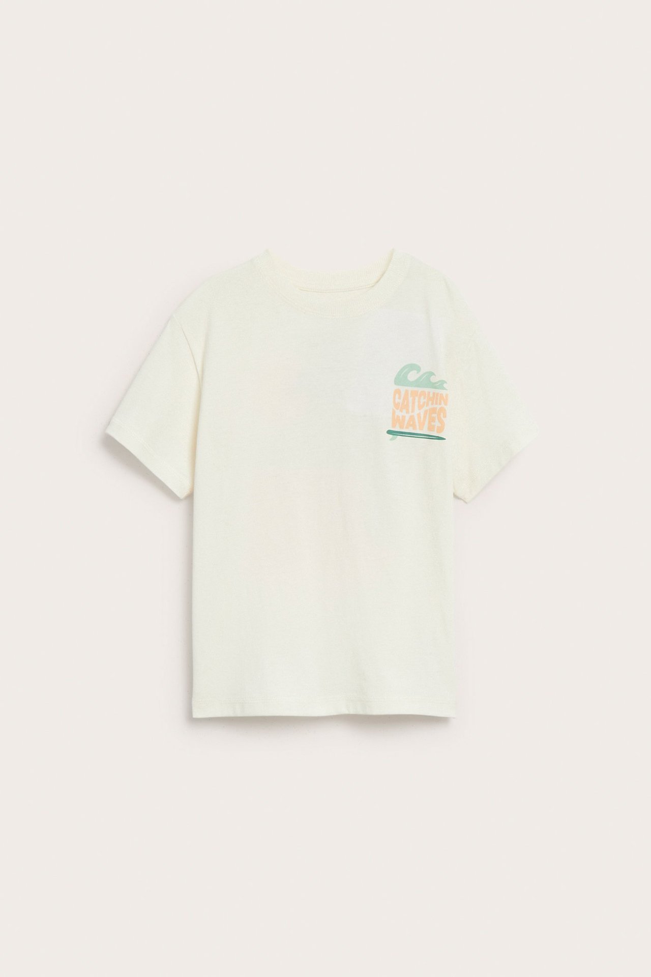Frontvy av en offwhite oversize t-shirt i bomull med "Catchin Waves" tryck på bröstet.