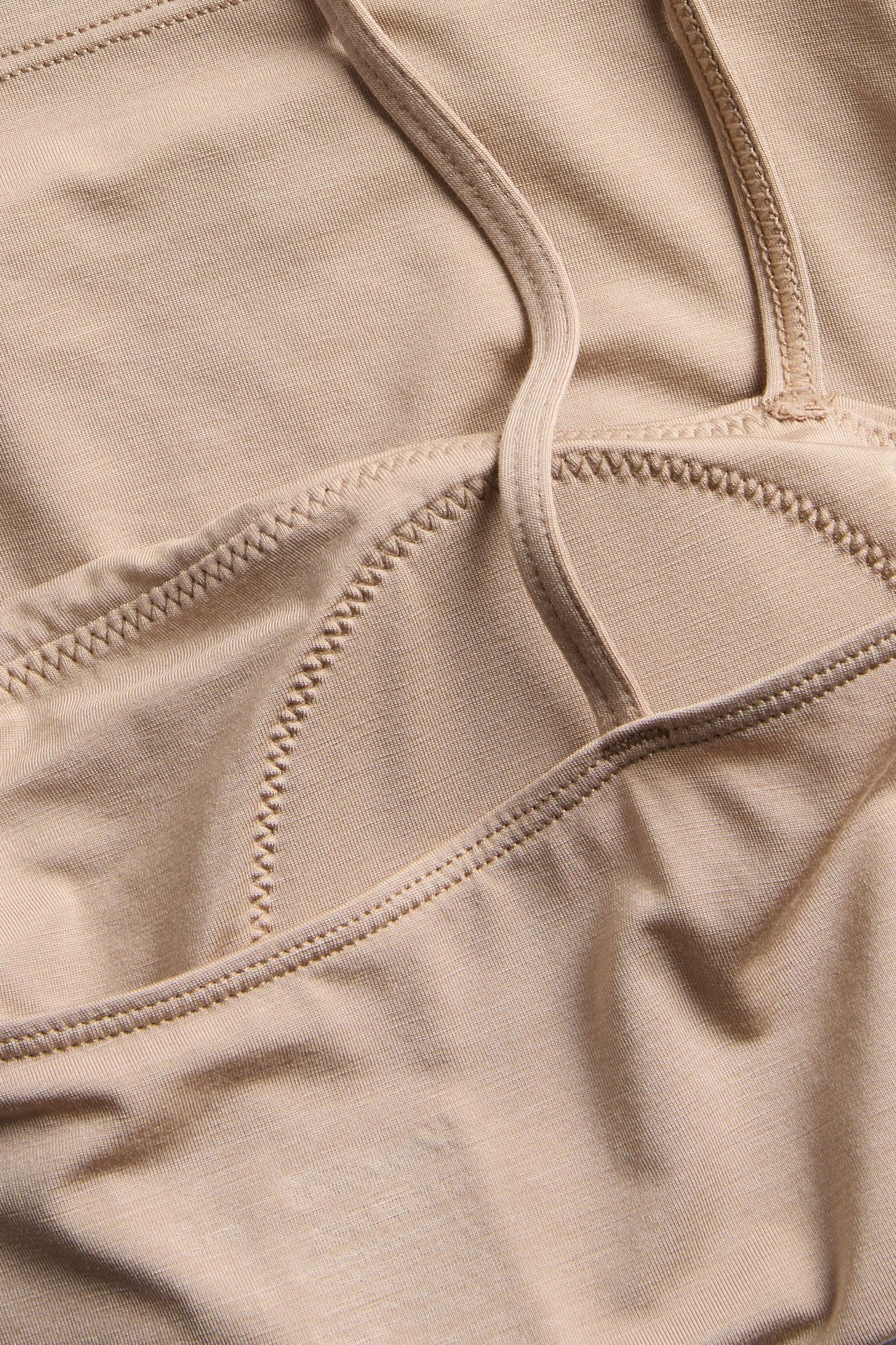 Zbliżenie na beżowy top z lyocellu z wbudowanym biustonoszem i regulowanymi ramiączkami.