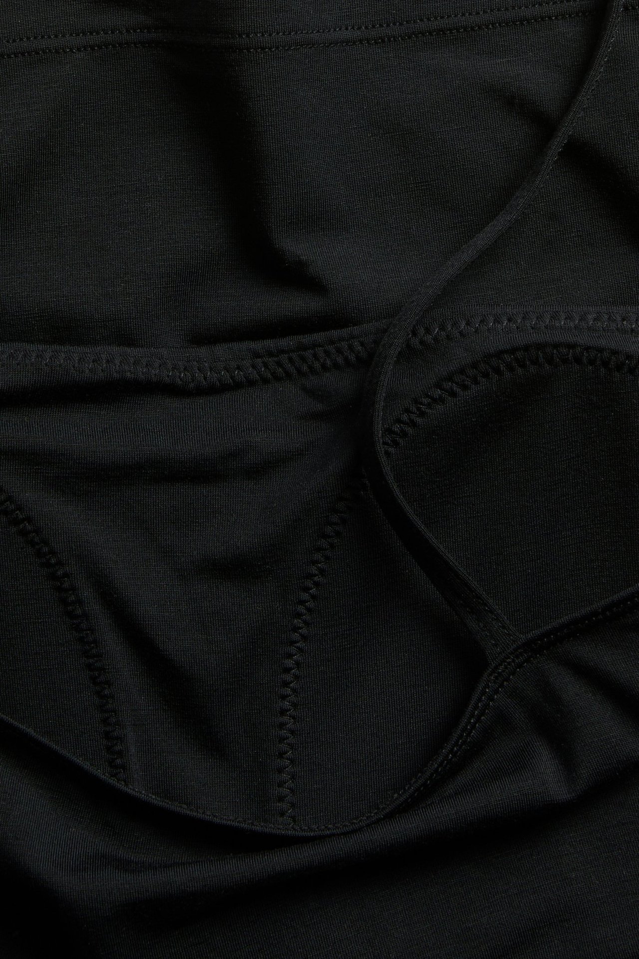 Närbild av ett svart linne i lyocellmix med inbyggd bh och synliga sömdetaljer.