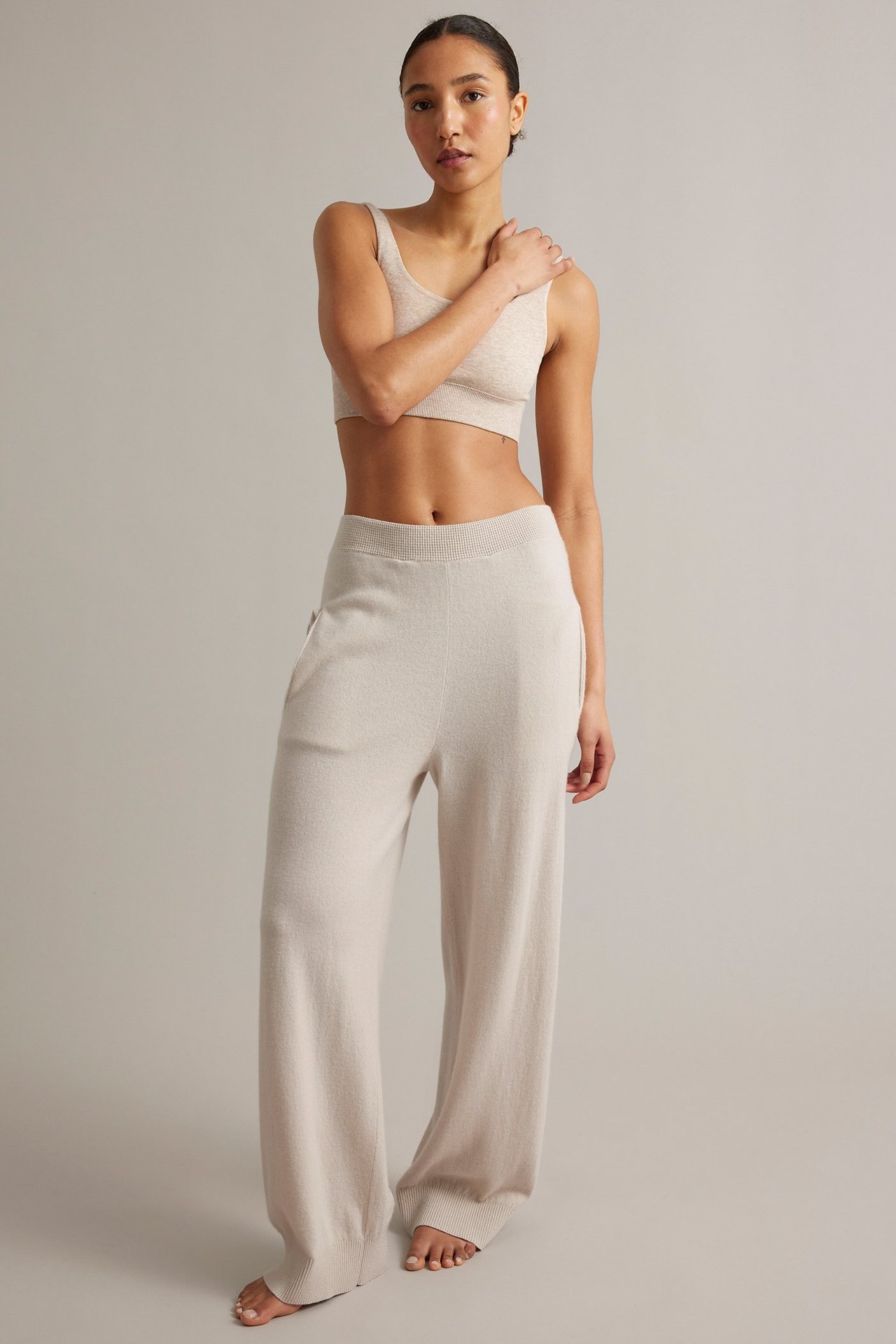 Framsida, kvinna i ljusbeige stickade vida byxor av ull/kashmirblandning med matchande crop top.