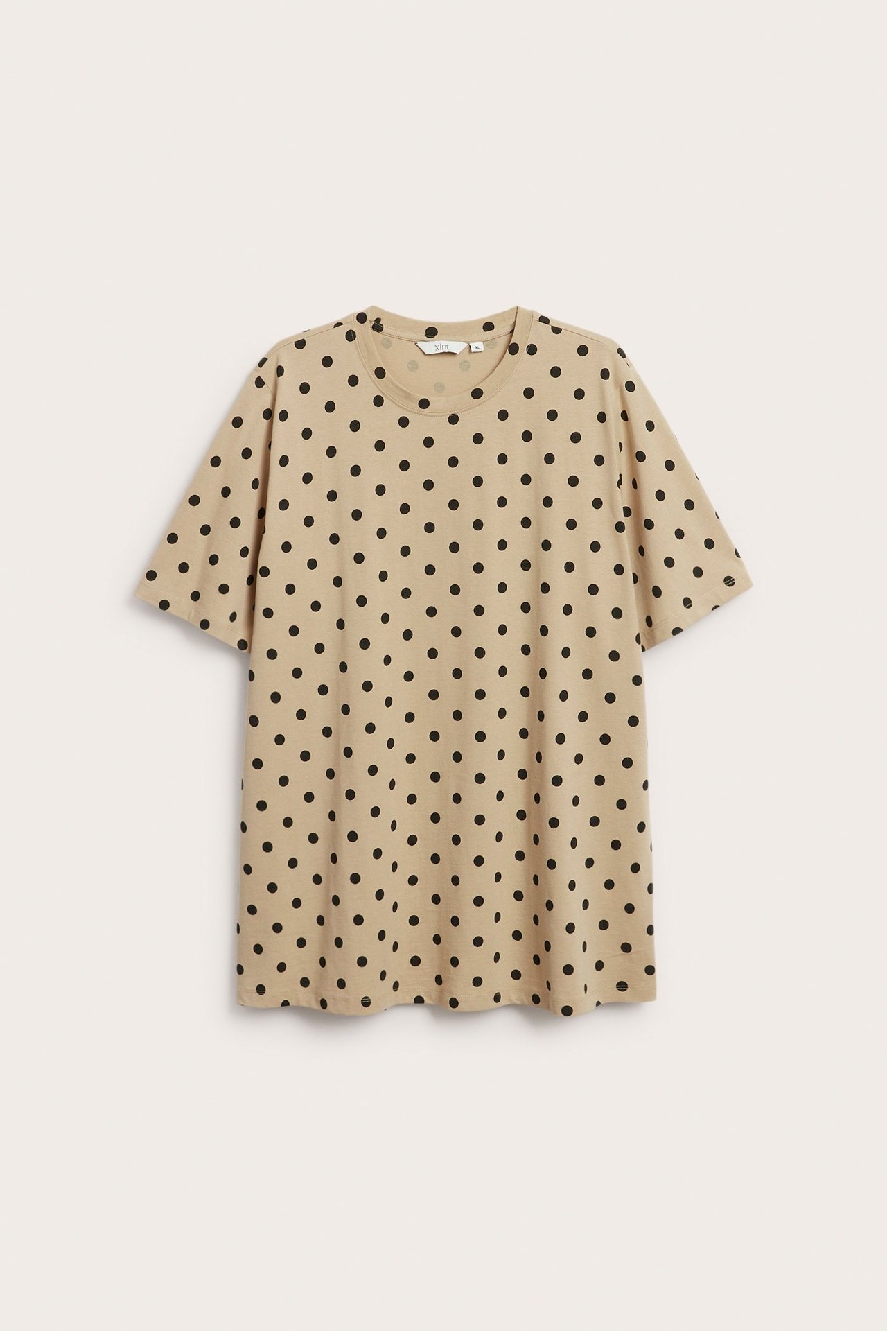 Forfra: Lang beige bomulls-T-skjorte med svarte prikker og rund hals.