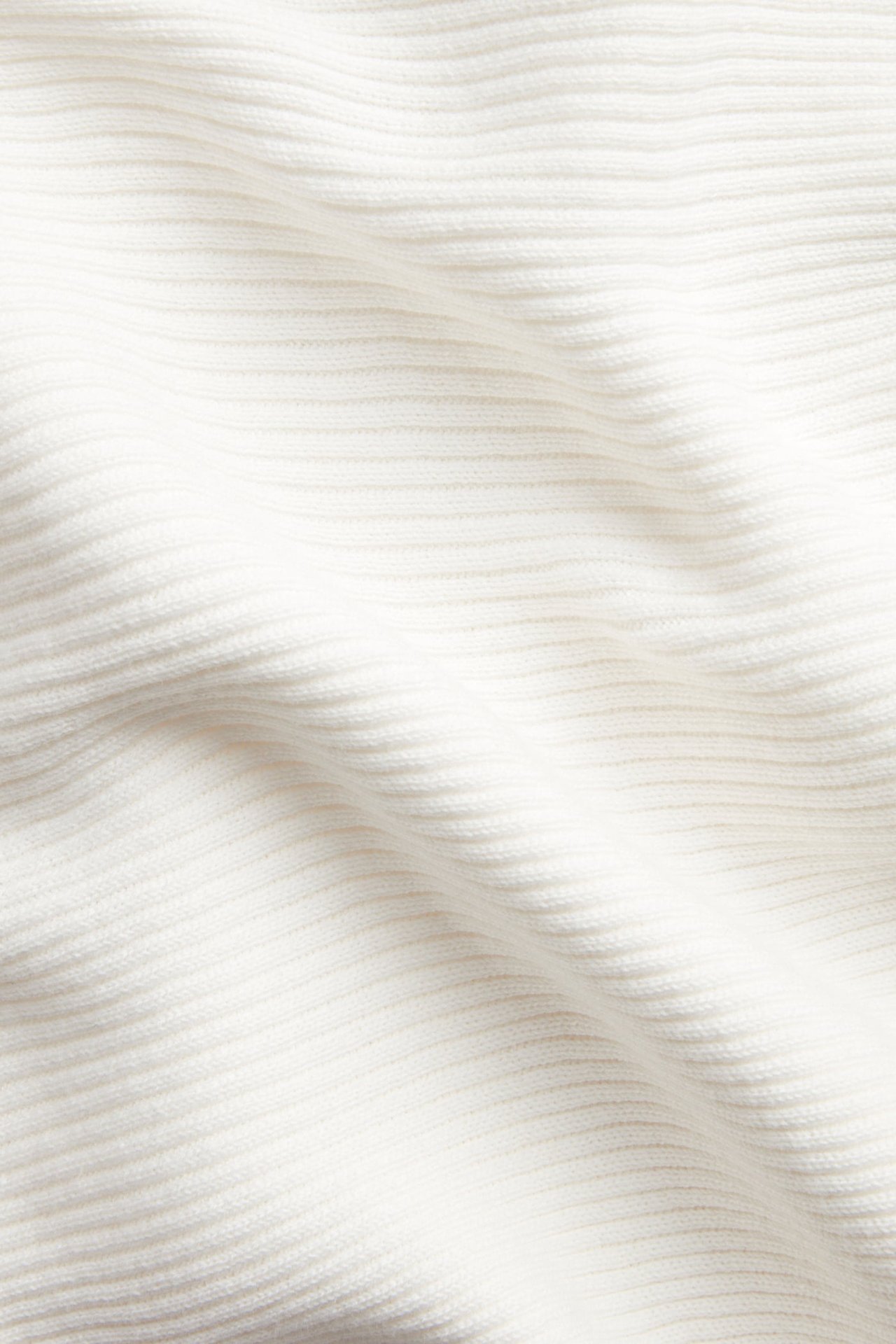 Zbliżenie na biały sweter w prążki, wykonany ze 100% bawełny, ukazujące jego teksturę.