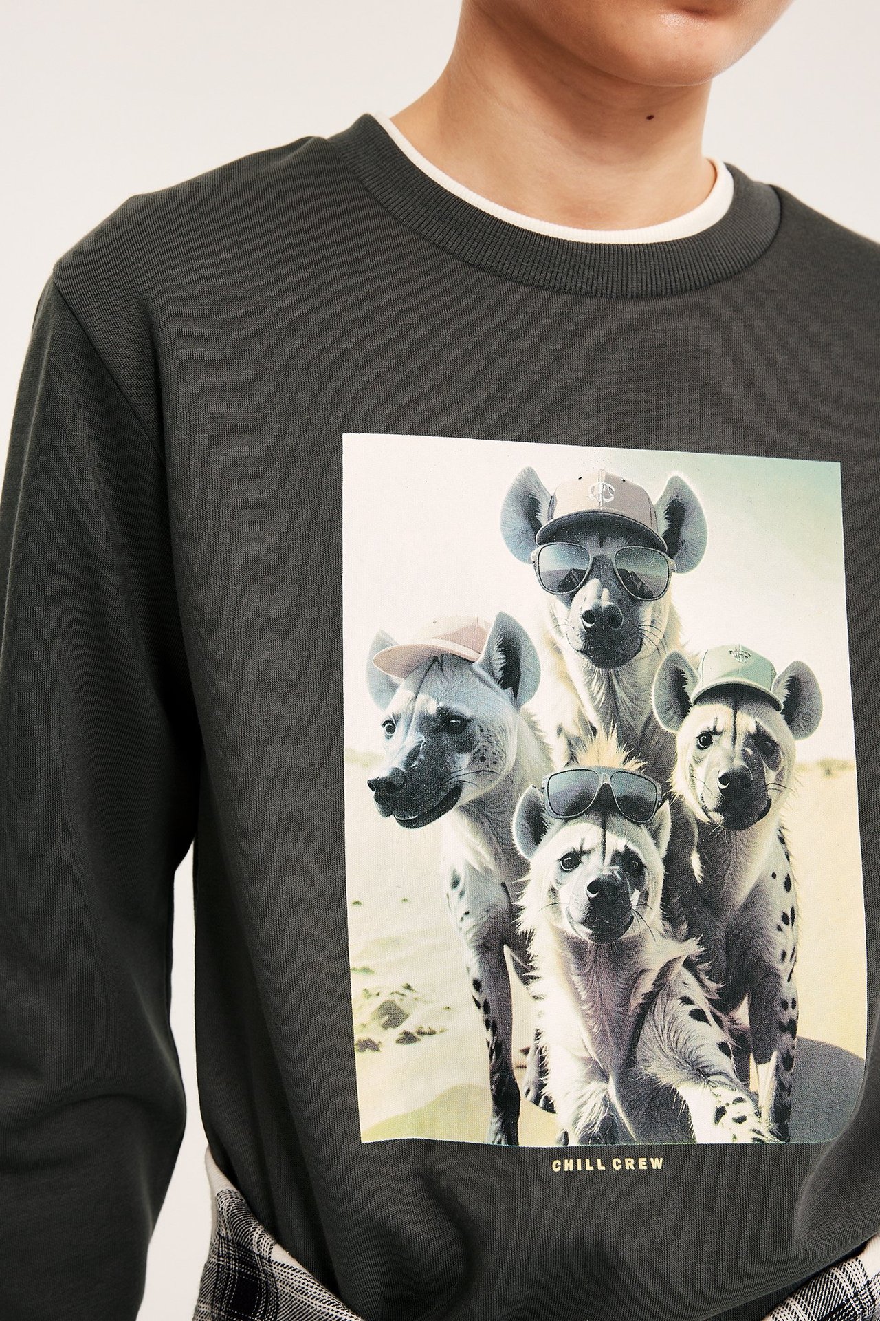 Frontutsikt: Barn bruker en svart sweatshirt med hyenetrykk, med hvit krage synlig.