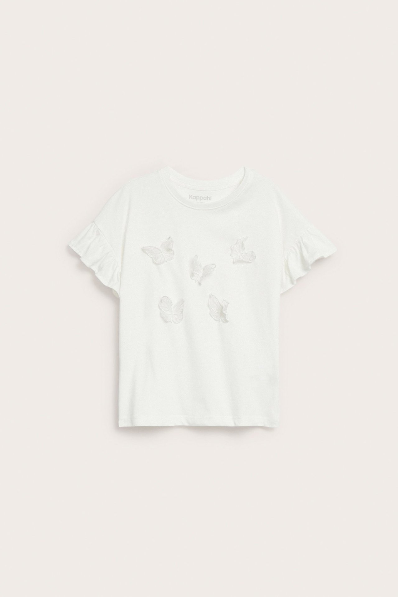 Widok z przodu na dziecięcy T-shirt bawełniany w kolorze złamanej bieli z falbankami i aplikacjami 3D.