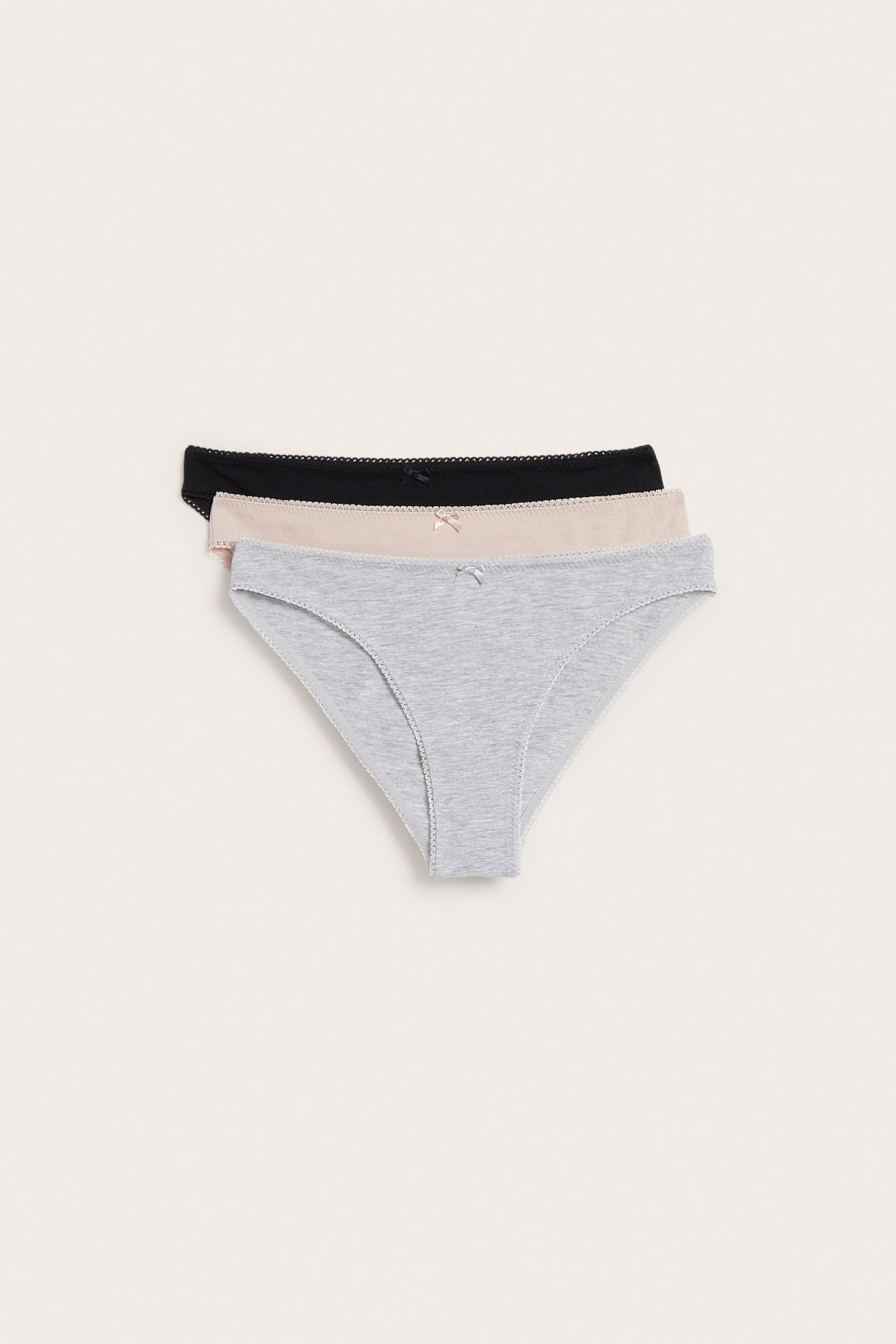 Ovenfra tre dameundertruser i bomull: grå, beige og svart, hver med picotkant og liten sløyfe.