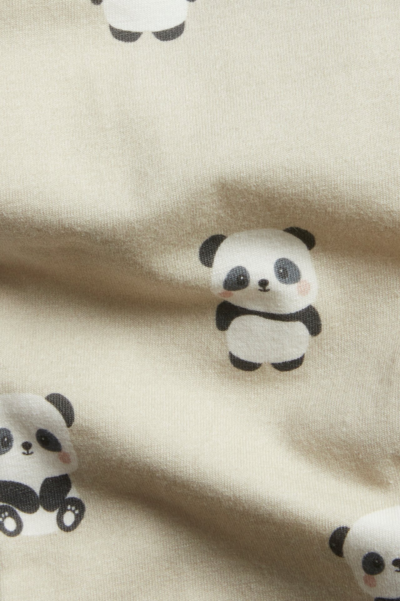 Nærbilde av beige baby-leggings i mykt jerseystoff med heldekkende panda-trykk.