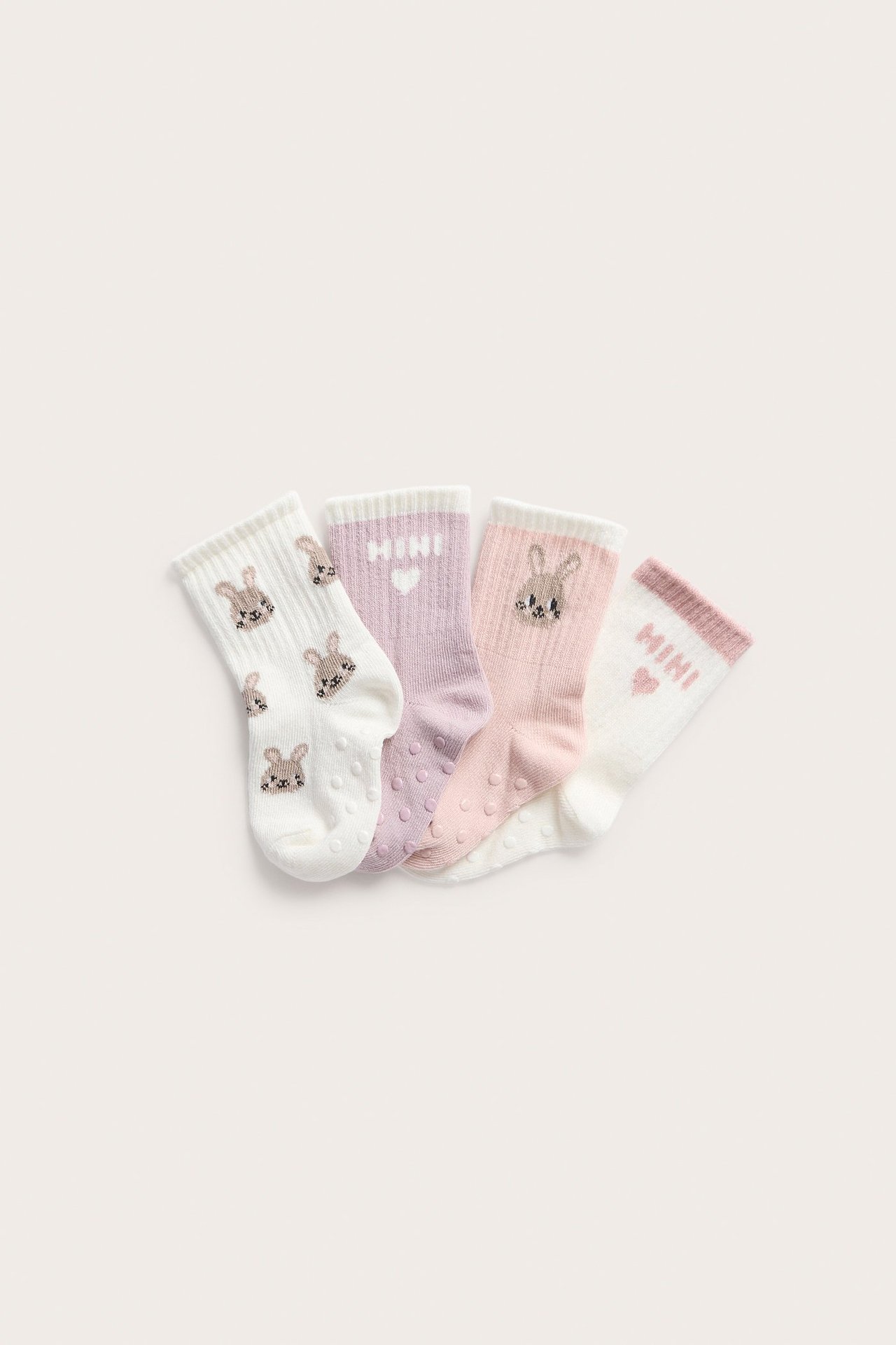 Ovenfra: Fire par mønstrede babysokker: hvite med kaniner, lys lilla, lys rosa og hvite med 'MINI'-tekst.