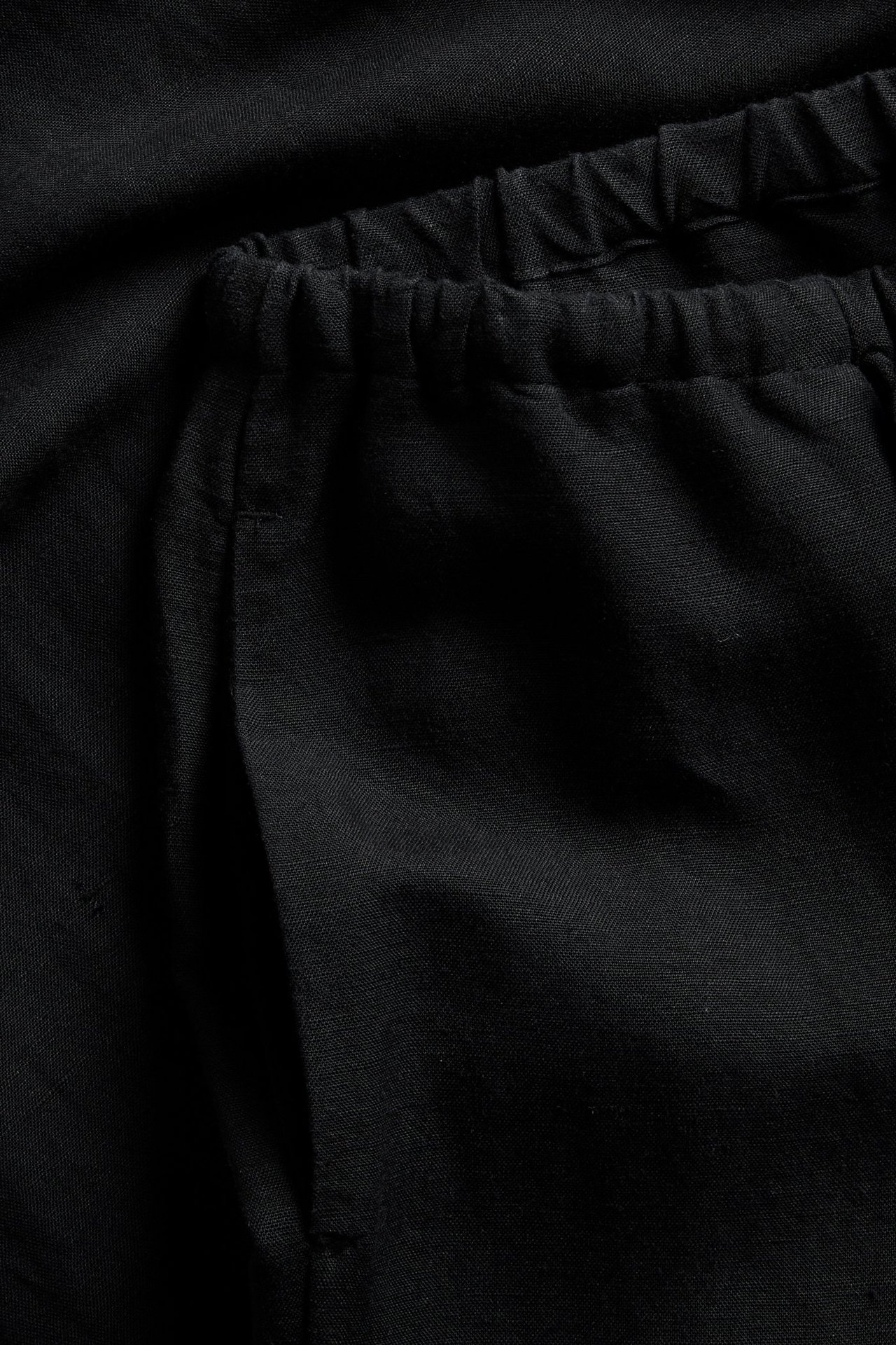 Närbild av svarta byxor i linnemix med resår i midjan och synlig sidoficka.