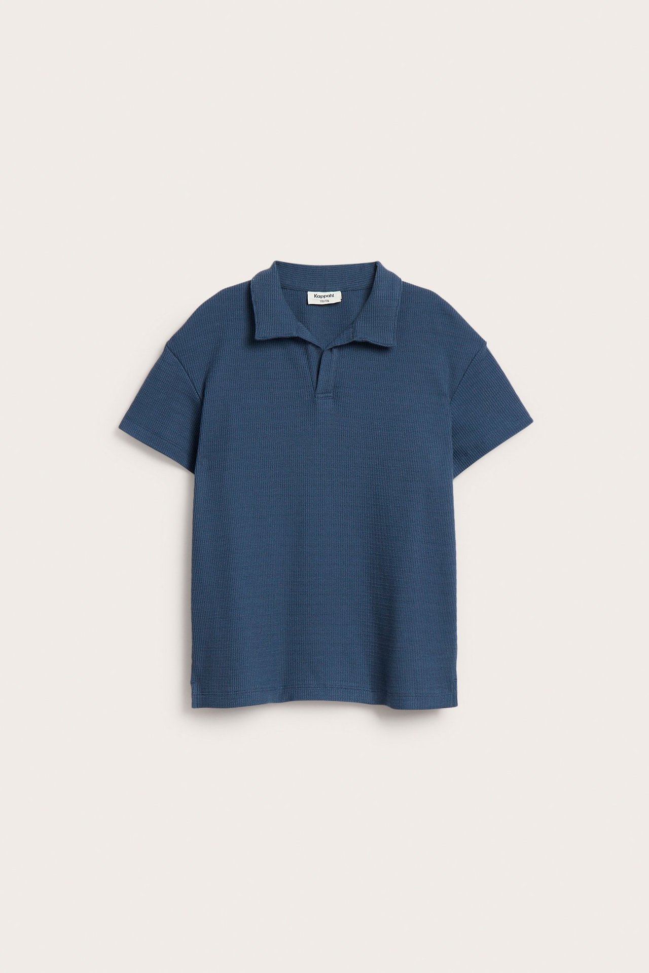 Framifrån, en blå, avslappnad pikétröja i strukturstickad bomull med V-ringning.