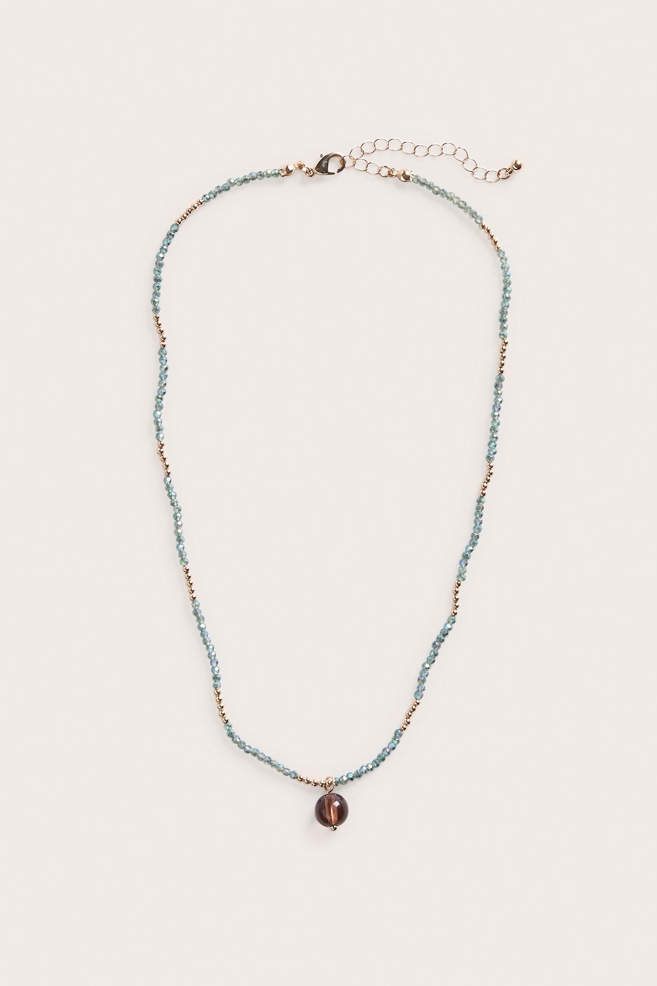 Widok z przodu: Złoty naszyjnik z jasnoniebieskimi szklanymi koralikami i ciemnobrązową szklaną zawieszką.