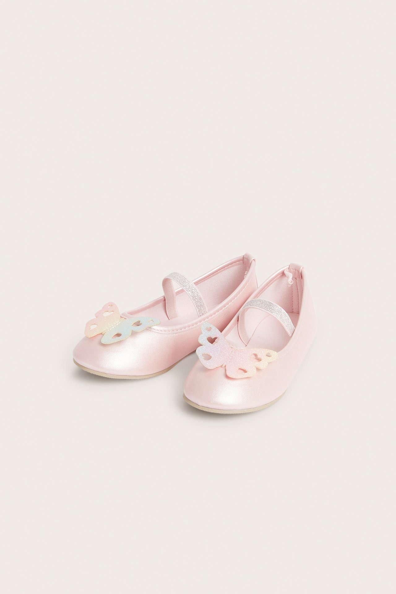 Edestäpäin, metallinhohtoiset vaaleanpunaiset ballerinat iiriksenhohtoisilla perhosapplikaatioilla ja kimalteremmeillä.