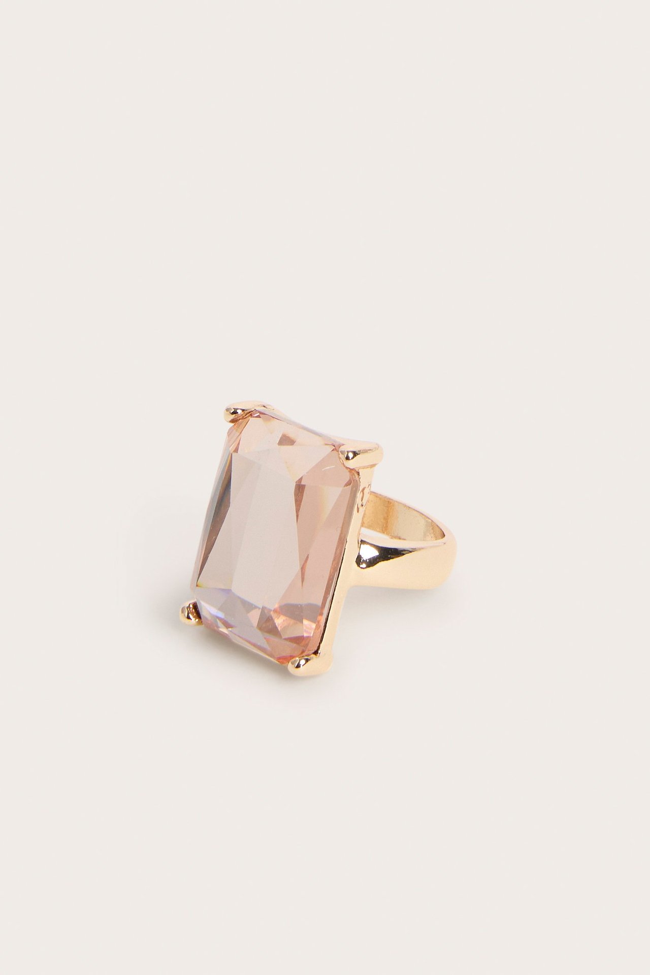 Nærbilde av en gullfarget damering med en stor rektangulær lys rosa plaststein.