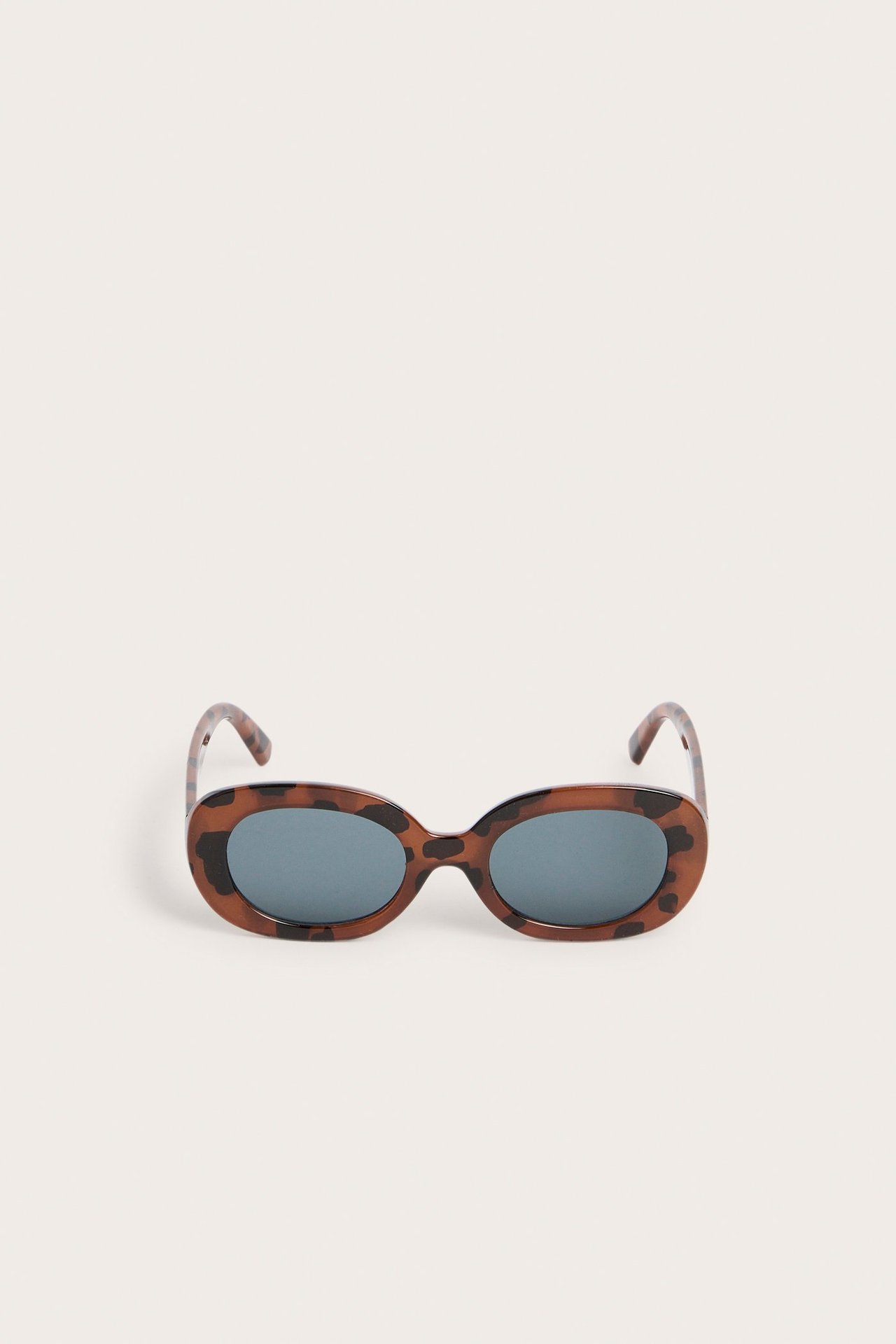 Frontvisning av brune skilpaddemønstrede ovale solbriller med mørke glass.