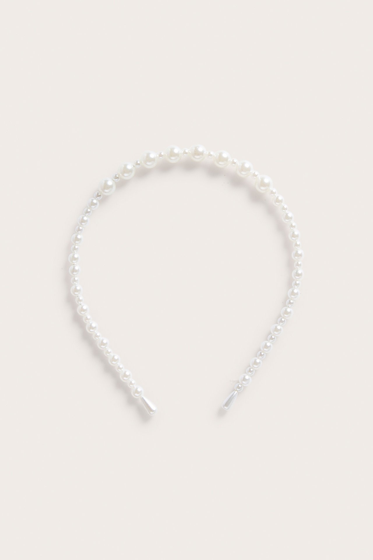 Opaska do włosów w kolorze złamanej bieli, z perłami o różnej wielkości, widok z przodu.