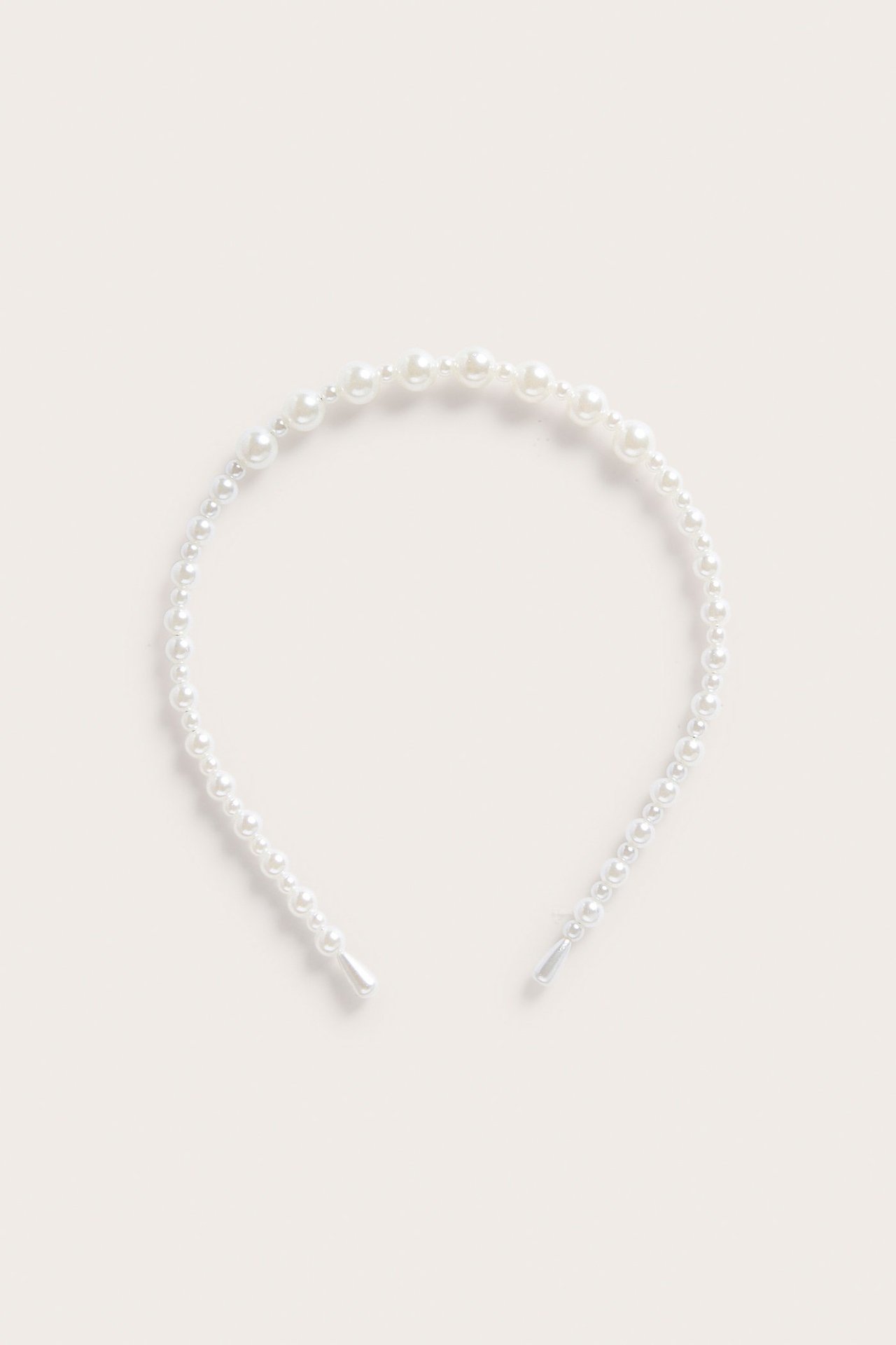 Edestä kuvattu luonnonvalkoinen helmipanta, jossa erikokoisia helmiä.