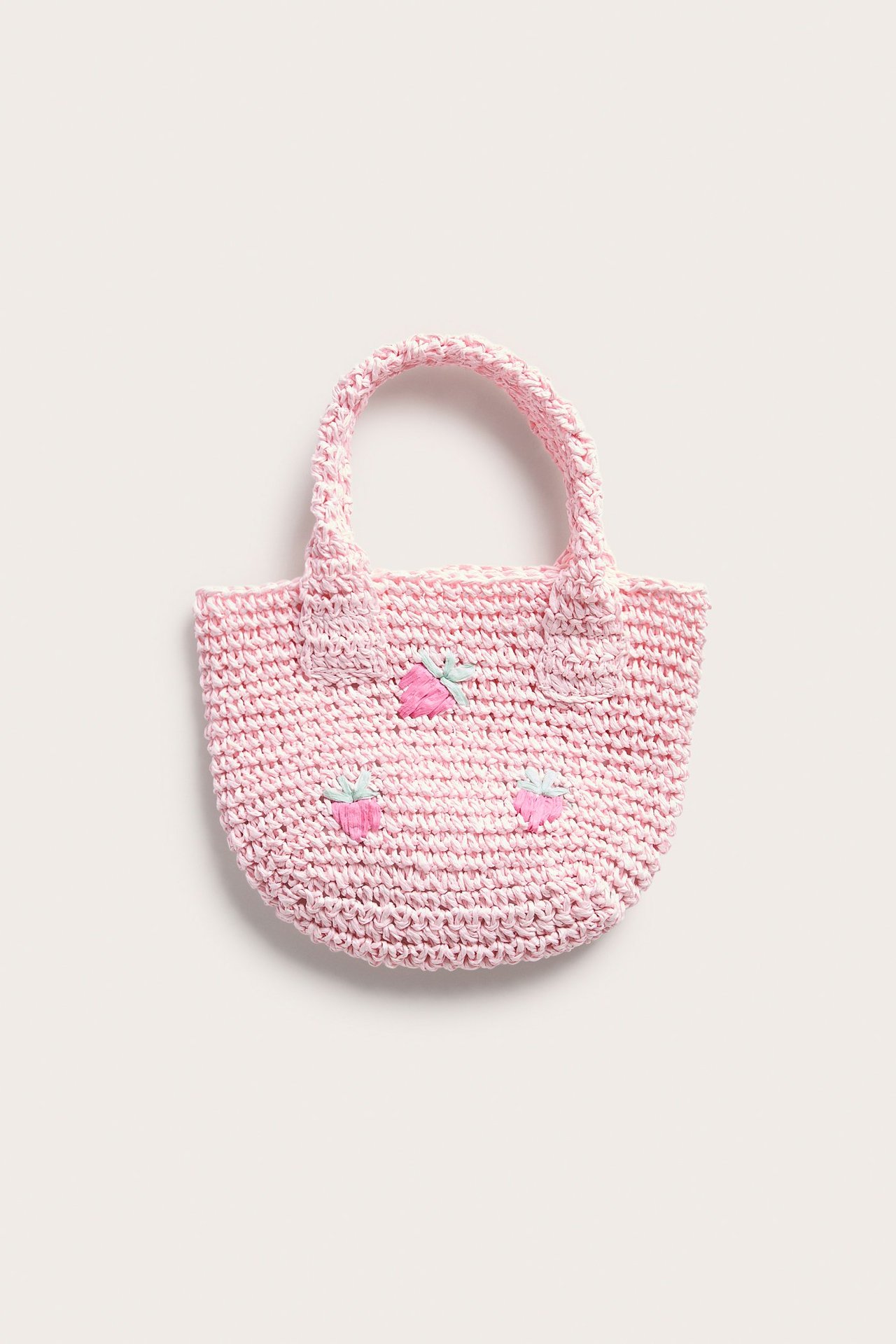 Widok z przodu różowej słomianej torebki z haftowanym wzorem truskawek i dwoma uchwytami.