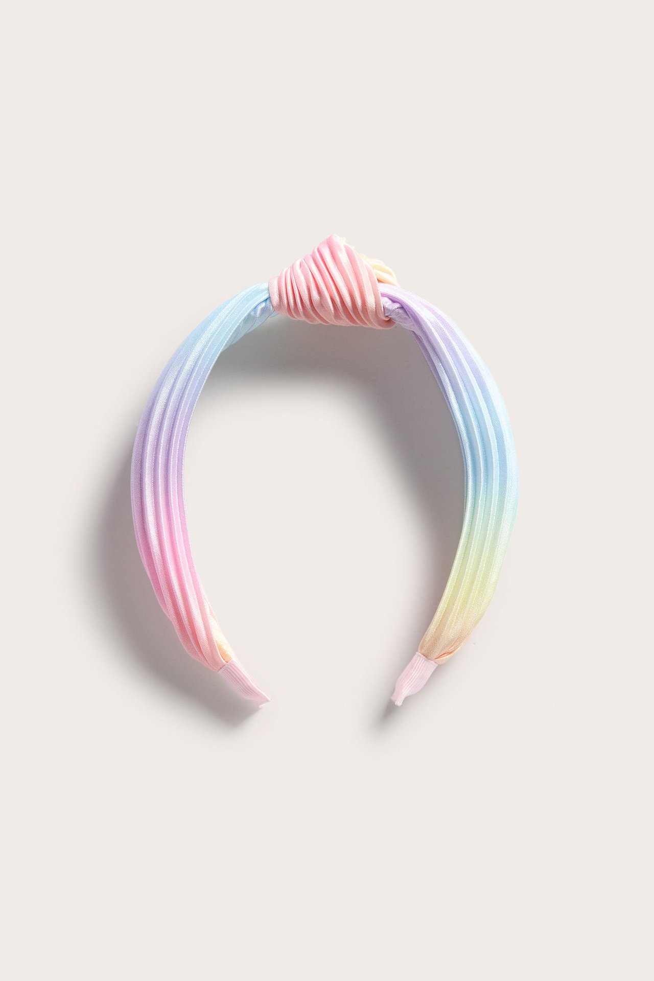 Lähikuva, ylhäältäpäin sateenkaarenvärisestä laskostetusta pannasta, jossa on koristeellinen solmu.