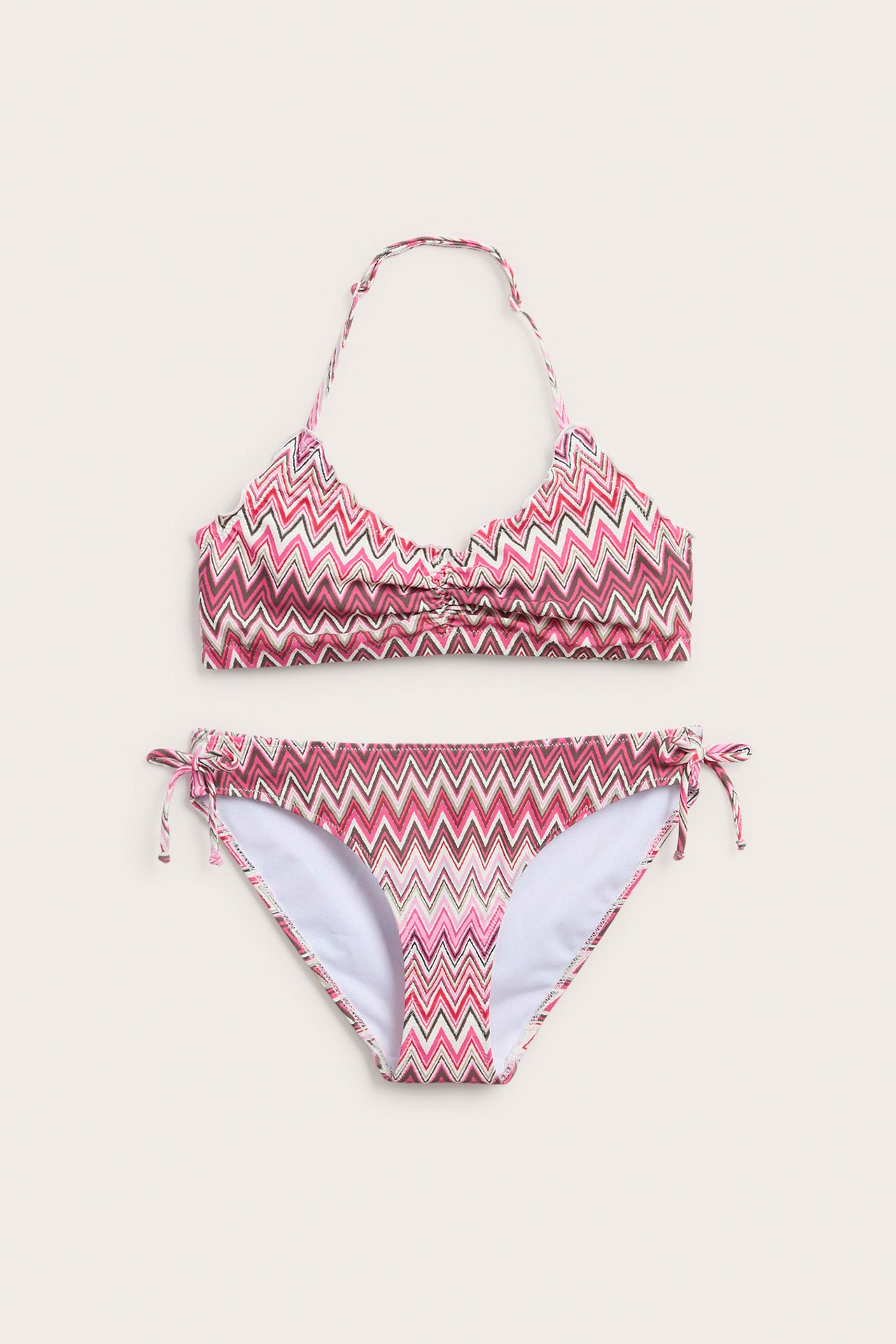 Widok z przodu: dziecięce różowe bikini w zygzaki, z marszczonym topem halterneck i wiązanymi majtkami.
