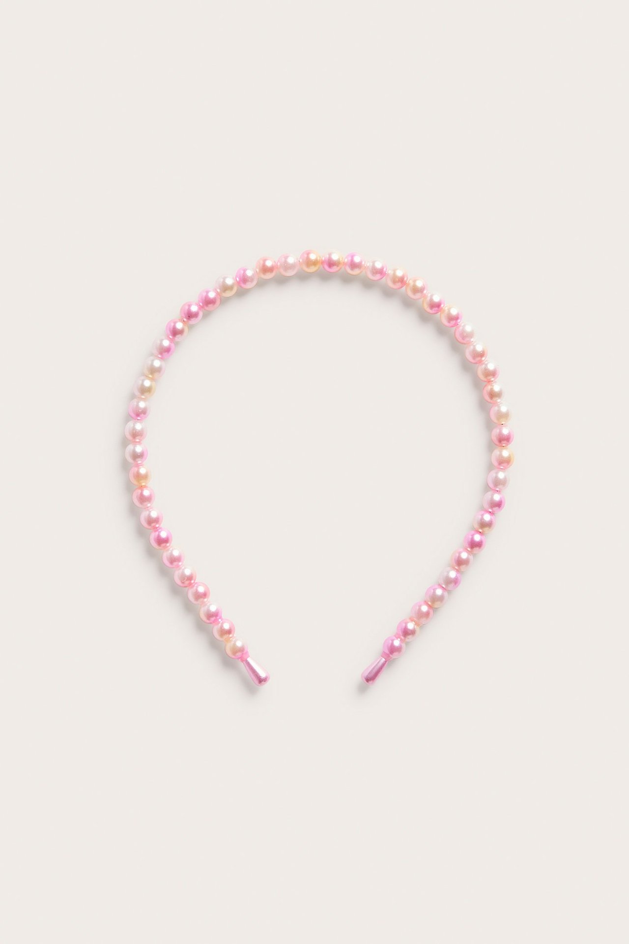 Tasokuva, ylhäältä: vaaleanpunainen panta, jossa irisoivia sateenkaarenvärisiä helmiä.