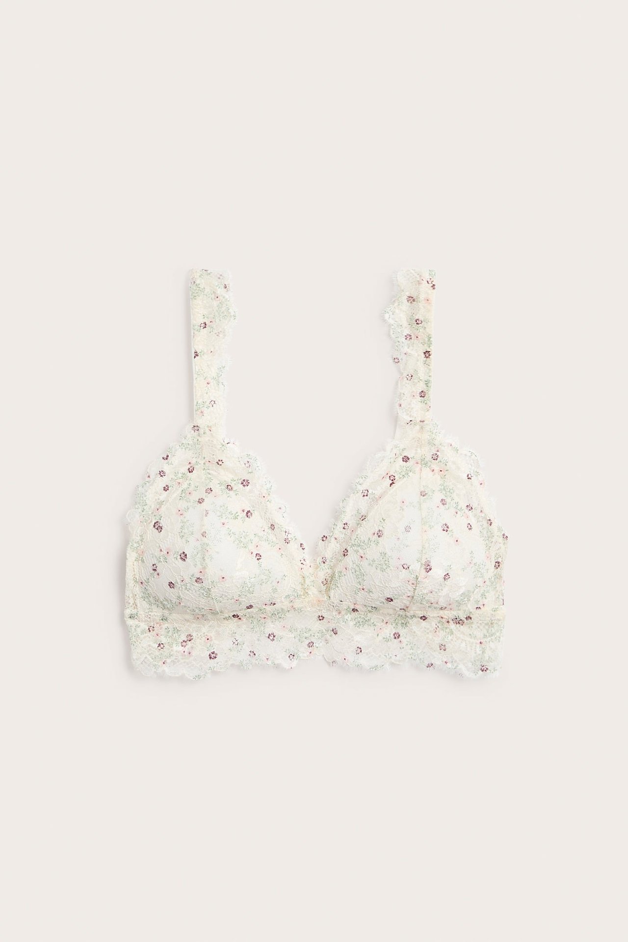 Edestäpäin valkoinen pitsibralette kukkakuviolla, topatuilla kaarituettomilla kupeilla ja säädettävillä olkaimilla.