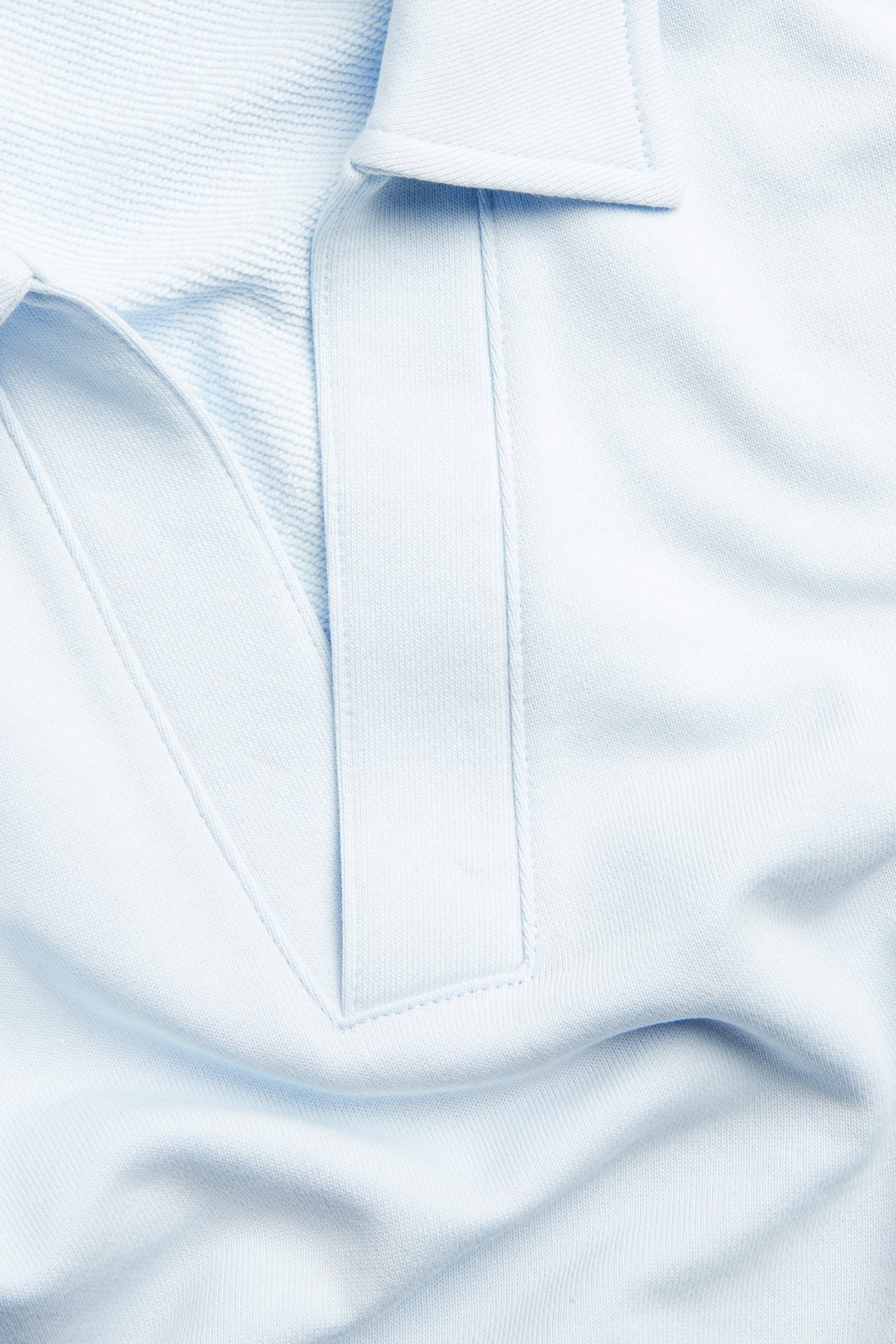 Zbliżenie jasnoniebieskiej bawełnianej bluzy z kołnierzykiem i dekoltem w serek.