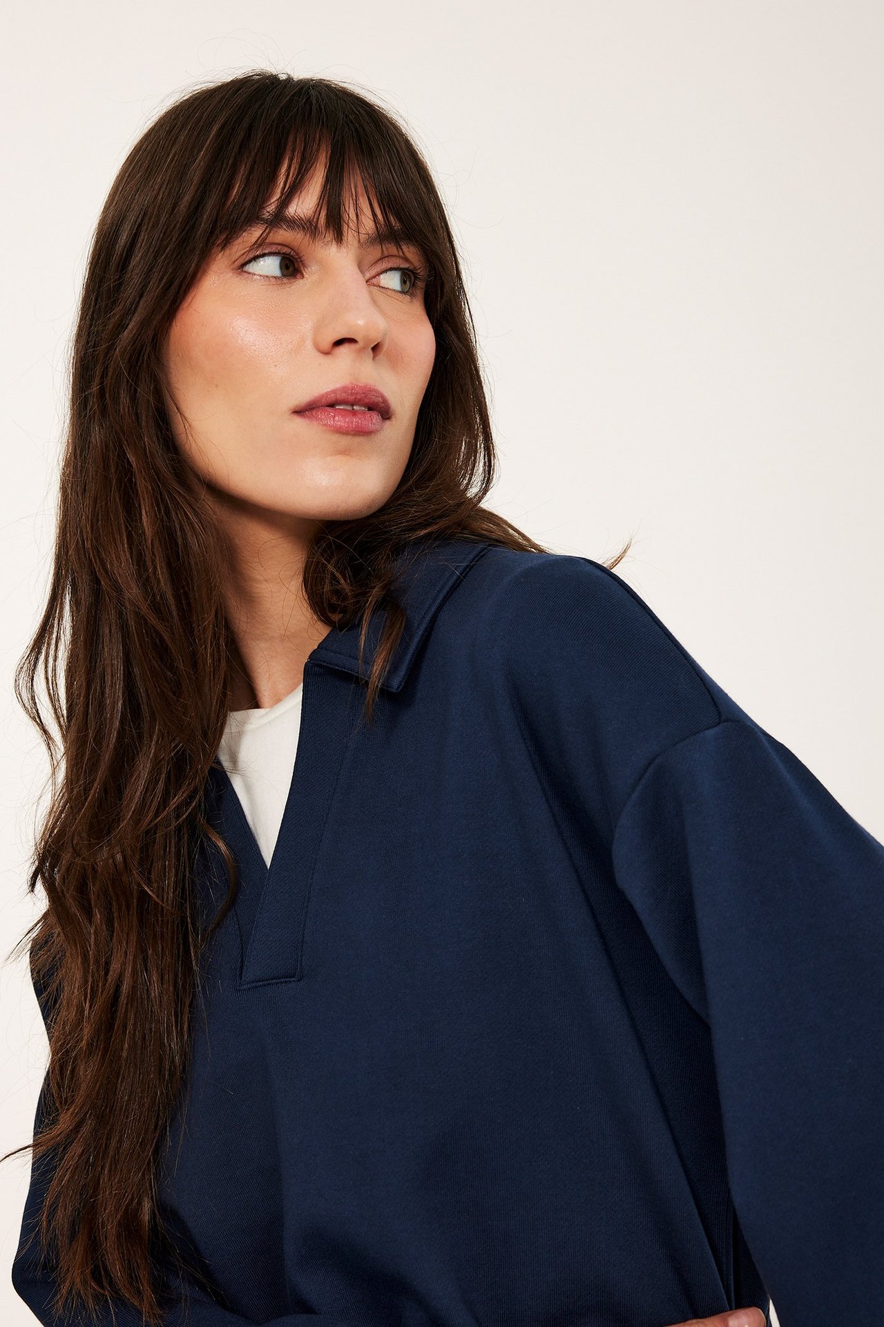 Lähikuva naisesta tummansinisessä pitkähihaisessa puuvillacollegepaidassa kauluksella, valkoisen paidan päällä.