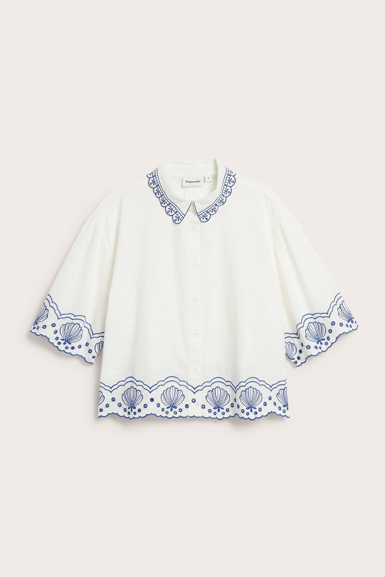 Widok z przodu: biała bawełniana koszula z krótkim rękawem, niebieski haft angielski na kołnierzu, mankietach i dole.